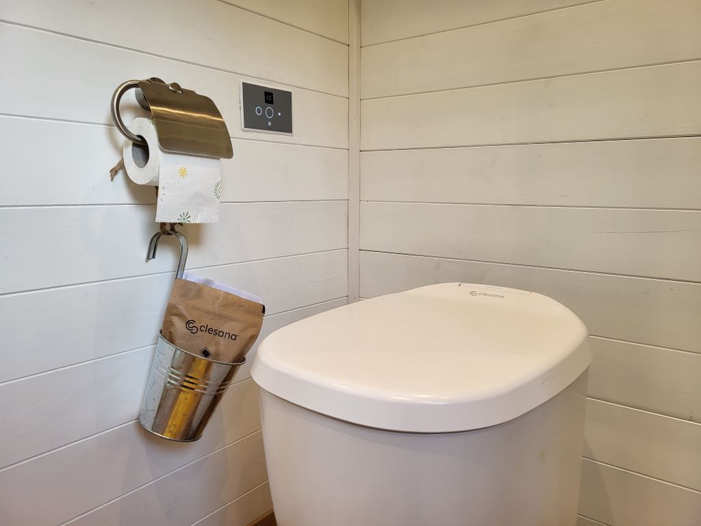 Waterless Clesana WC with bag welding in a room with wood paneling.