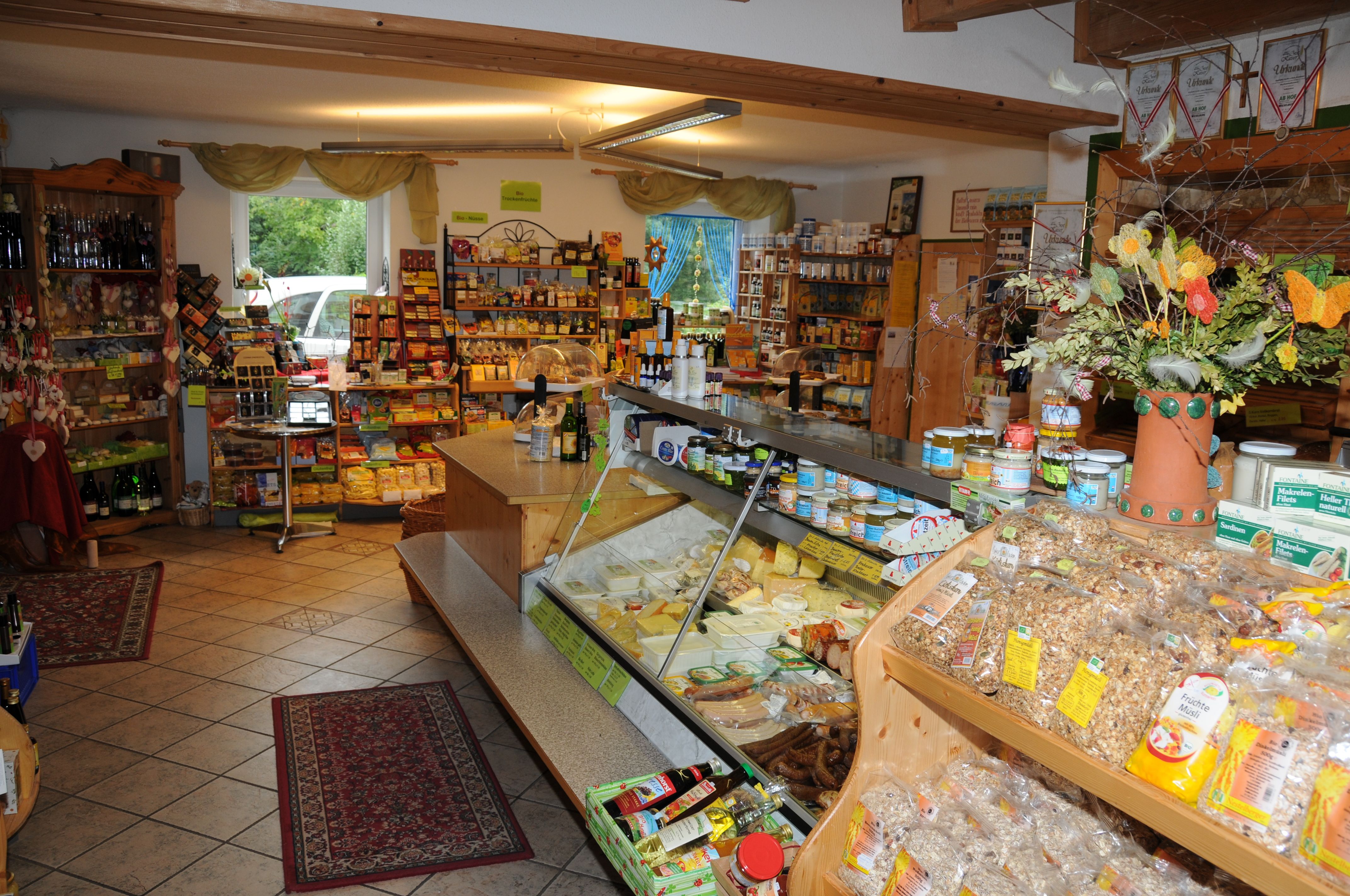 Interior view of an organic farm store with shelves full of products and a counter with cheese and sausage.
