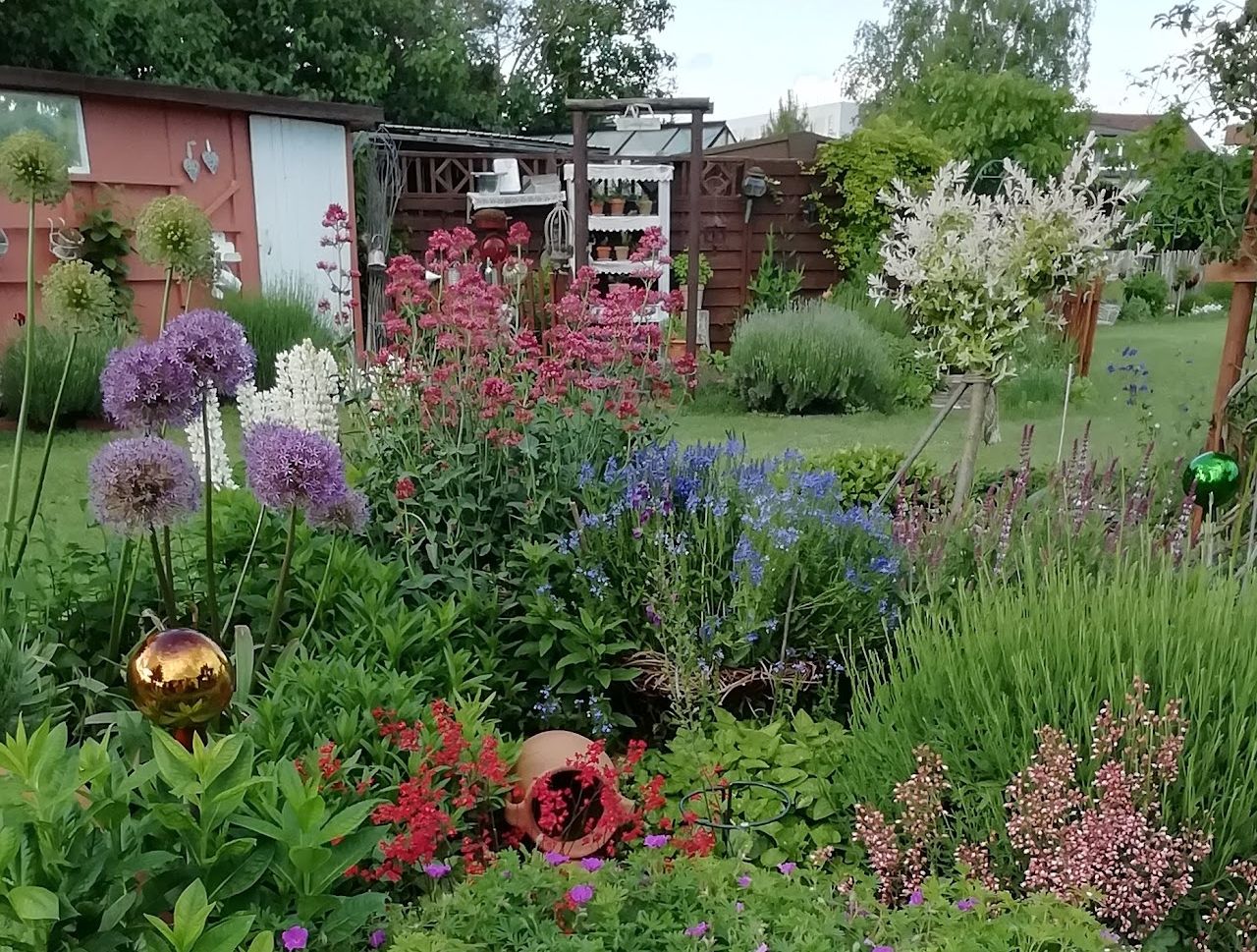 A lush perennial bed with colorful flowers and decorations in a garden.