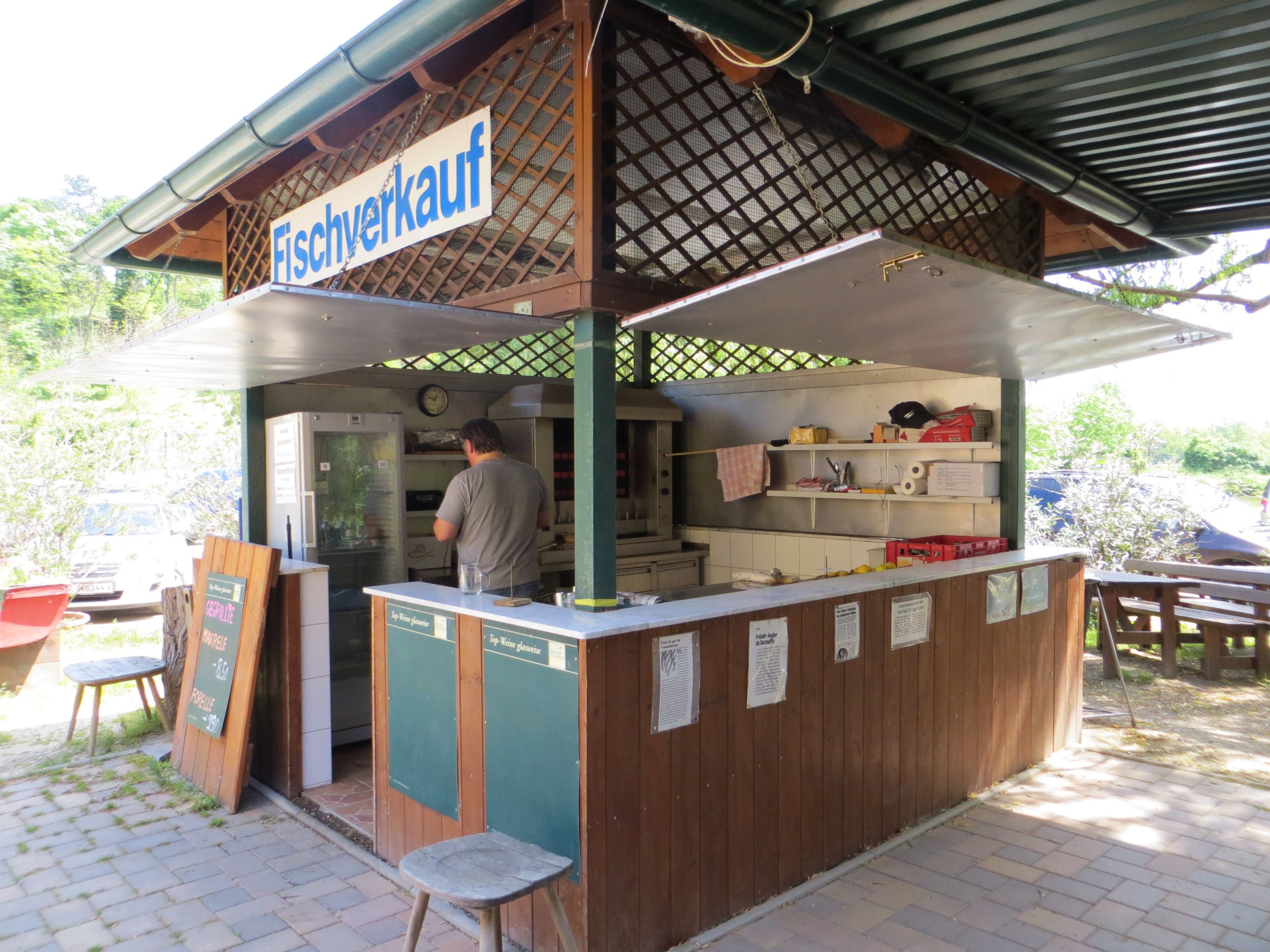 A small outdoor fish stall with a man working inside.