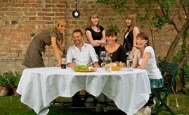 Group of six people sitting and standing around an outdoor table.