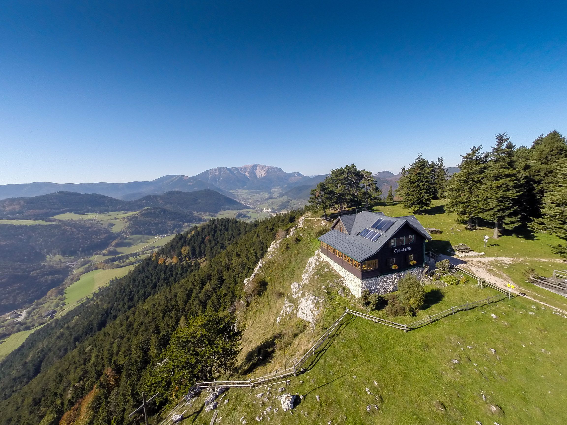 Hut on a hill with mountain landscape in the background.