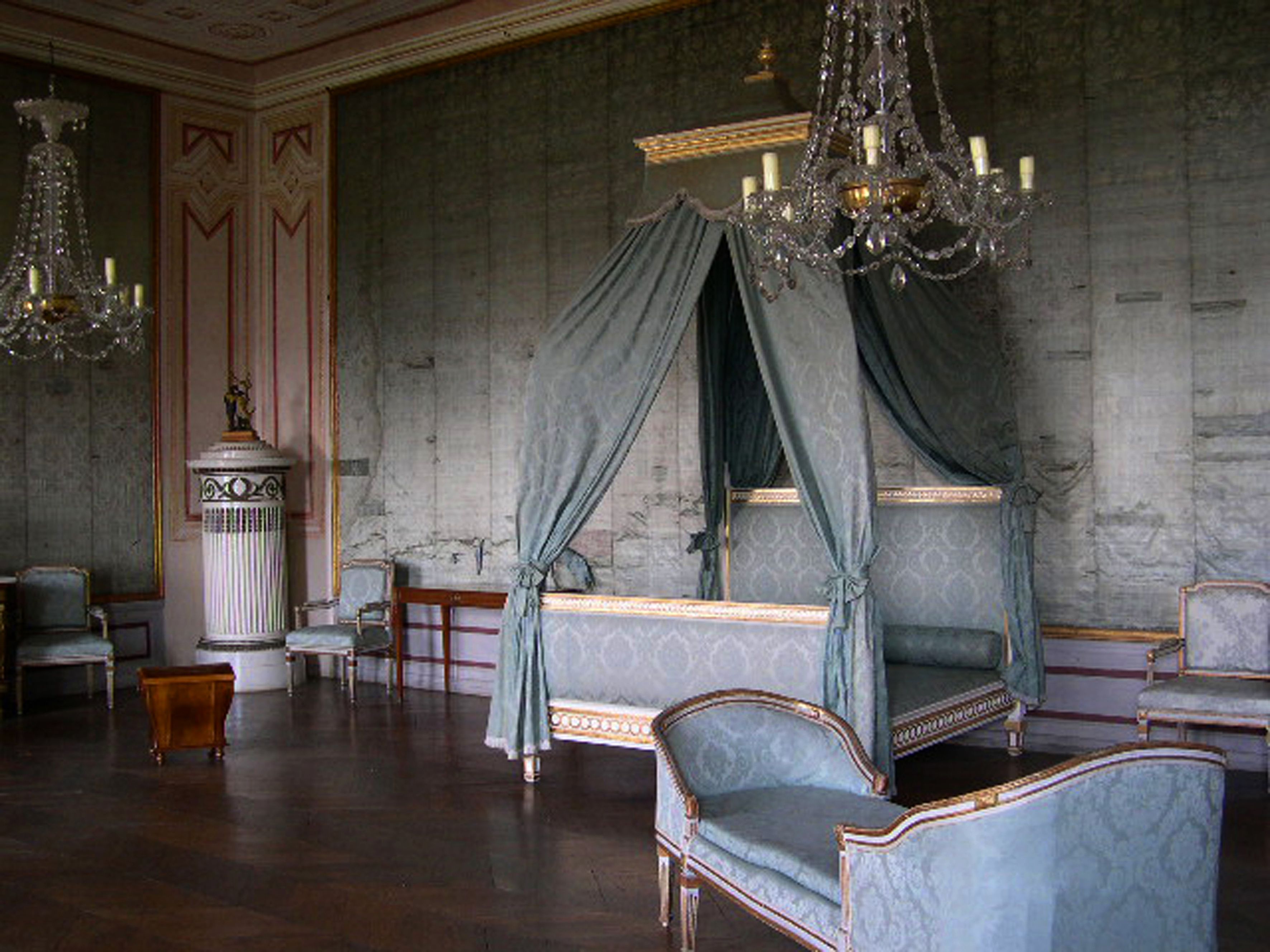 An elegant room in Loosdorf Castle with a four-poster bed, antique furniture and chandeliers.
