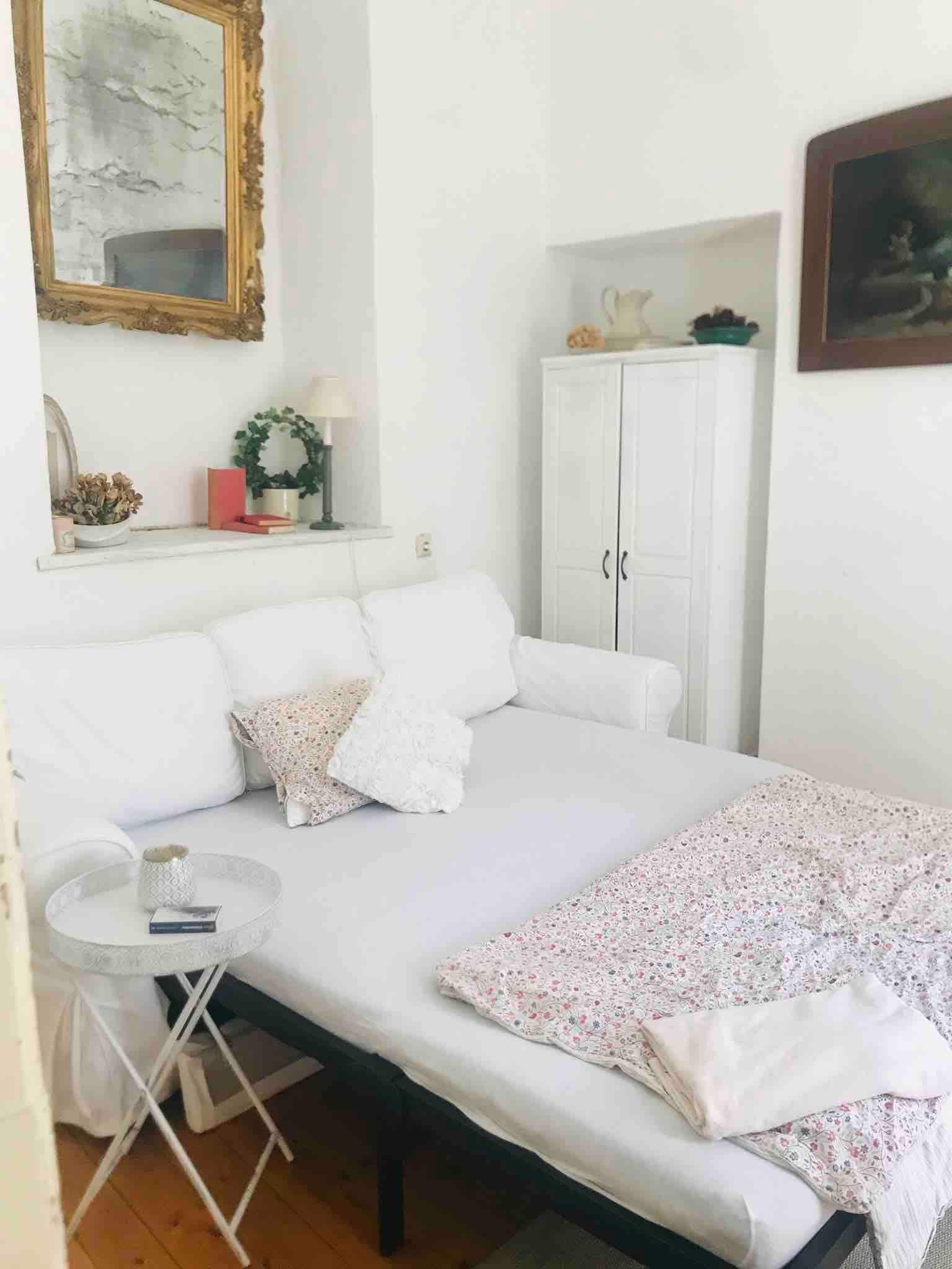 Cozy sleeping area with white sofa, side table and decorative elements.