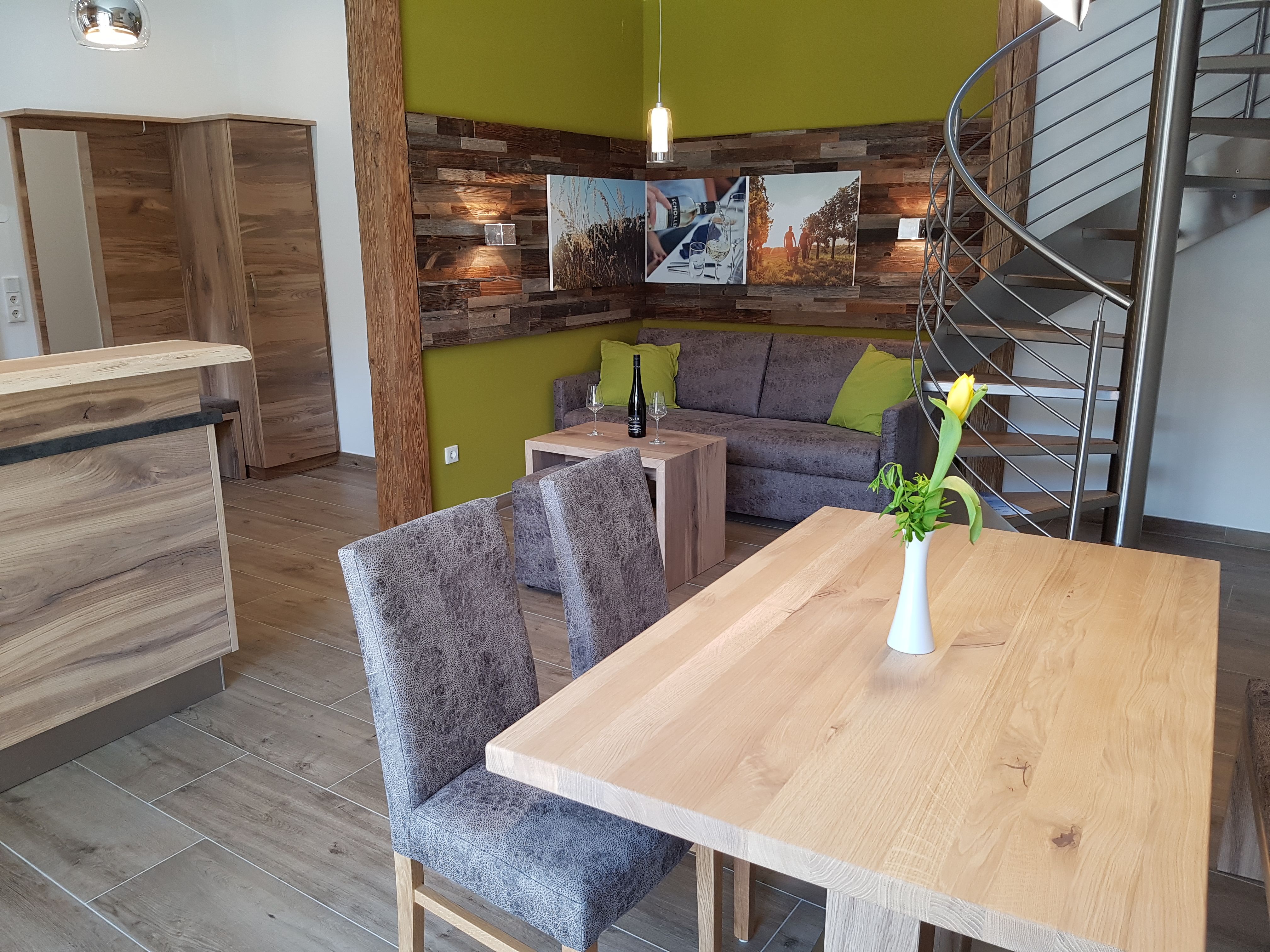 Modern apartment with wooden furniture, gray sofa, yellow wall and spiral staircase.