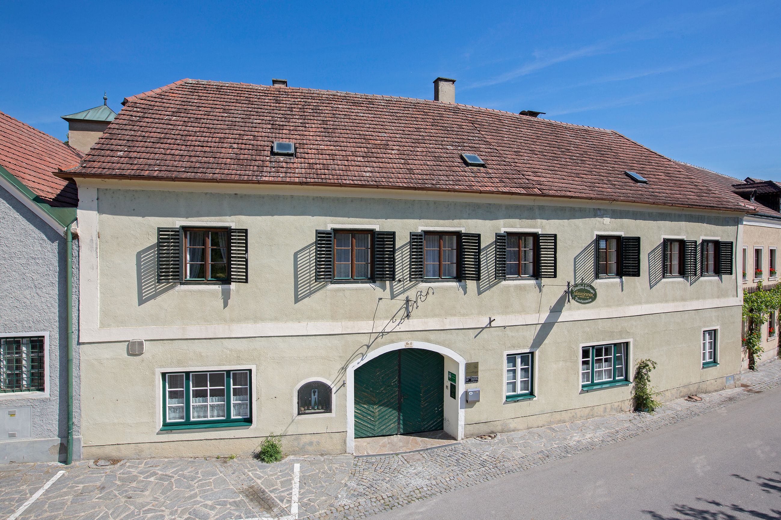 Exterior view of a traditional building with green gate and shutters.