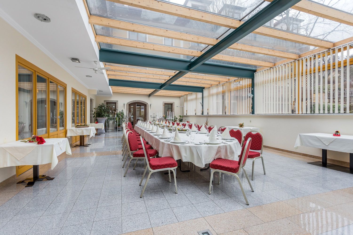 Elegant conservatory with table setting and red chairs.