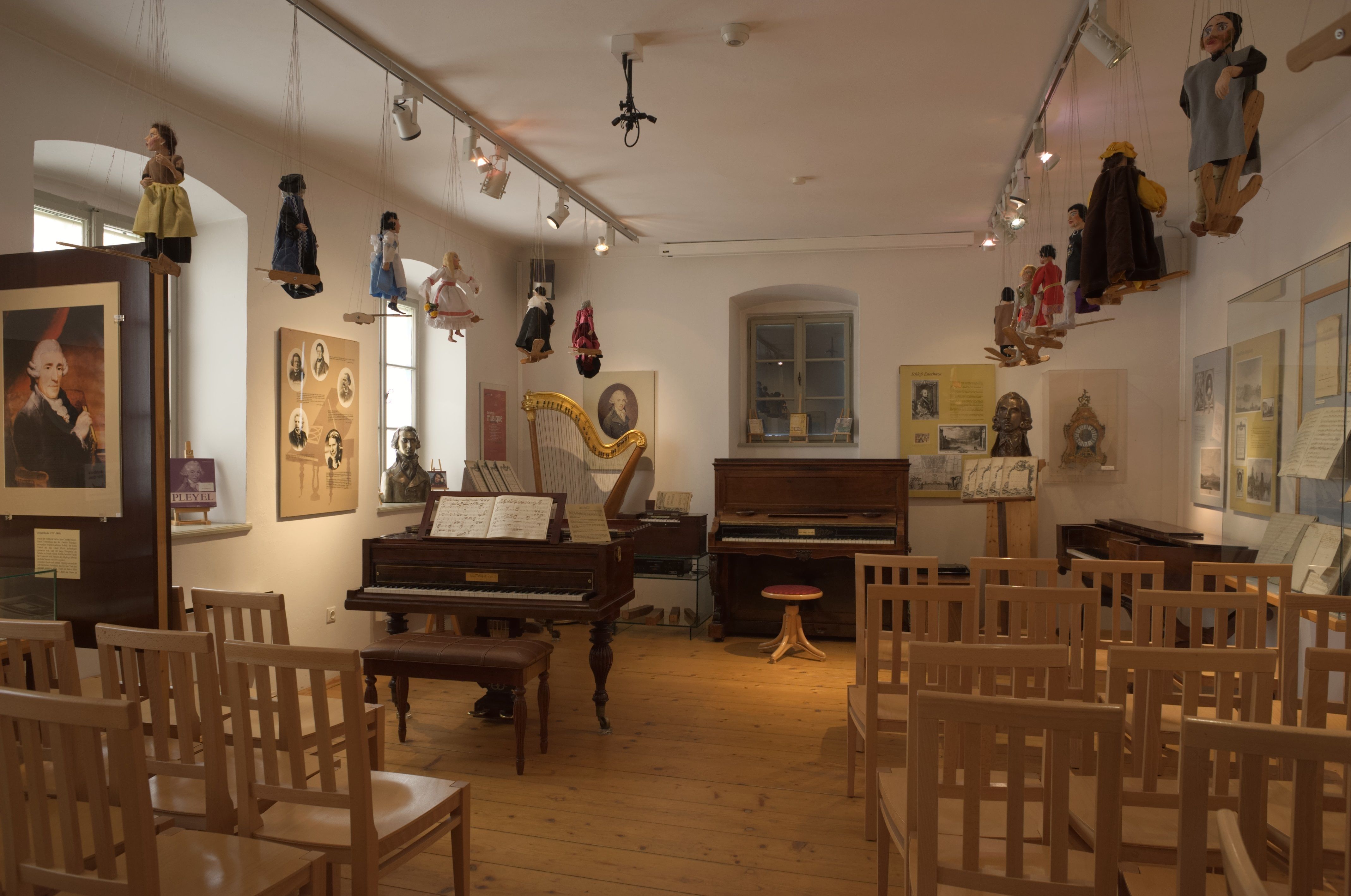 Interior shot of a museum room with musical instruments, dolls and chairs.
