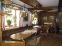 A traditionally furnished room with wooden furniture, plants on the windowsill and hanging lamps.
