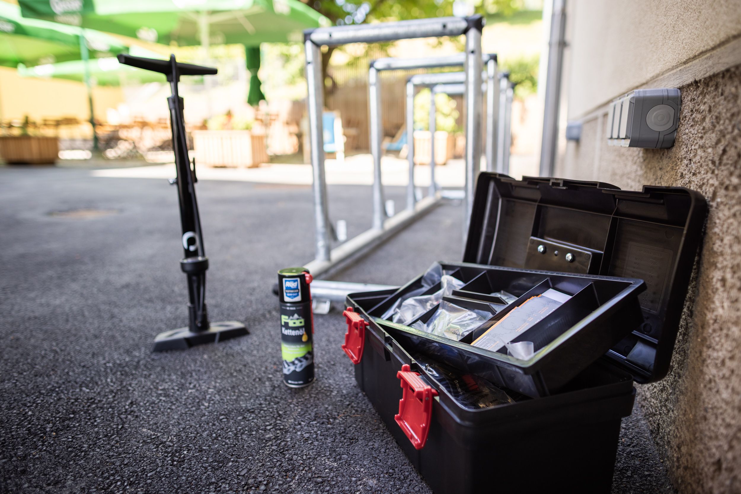 Bicycle tools, chain oil and pump next to bicycle racks outside.