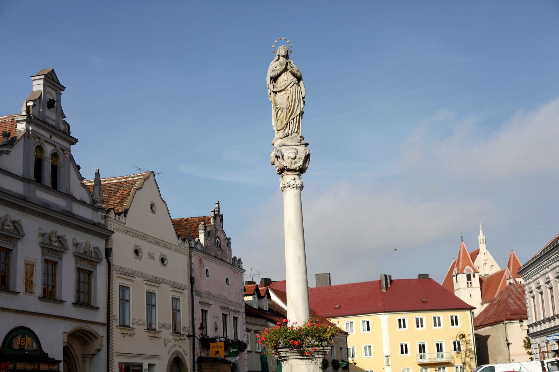 Statue on a pillar in Eggenburg with historical buildings in the background.