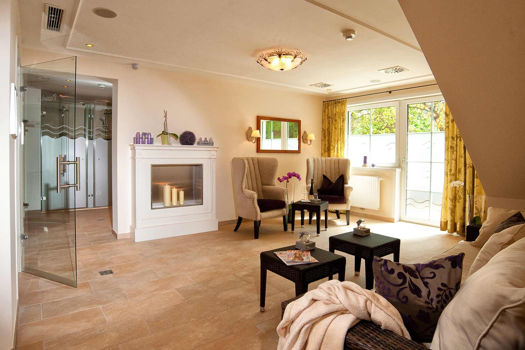 Elegant wellness area with fireplace, armchairs and glass door.