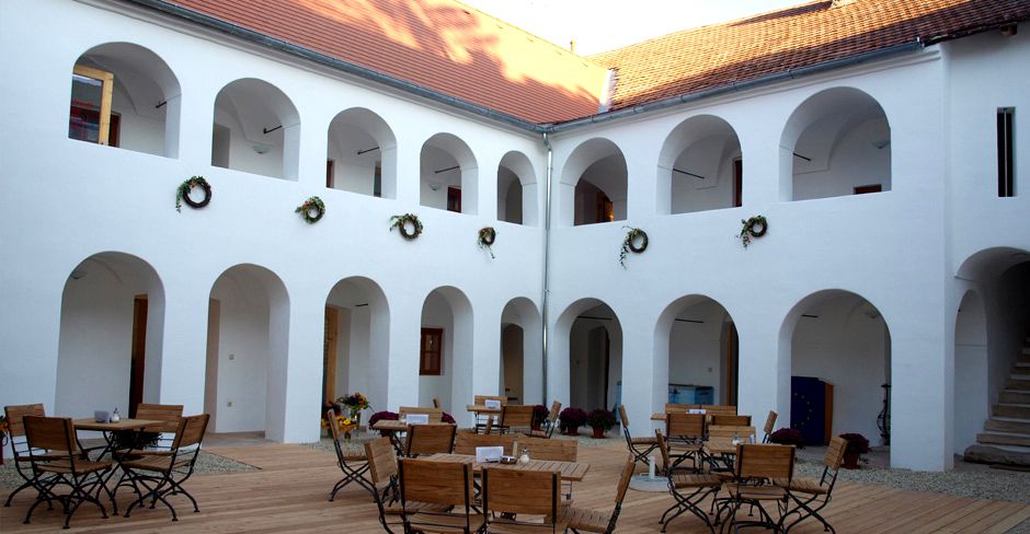 Inner courtyard of the Eisenhuthaus with arcades and wooden furniture.