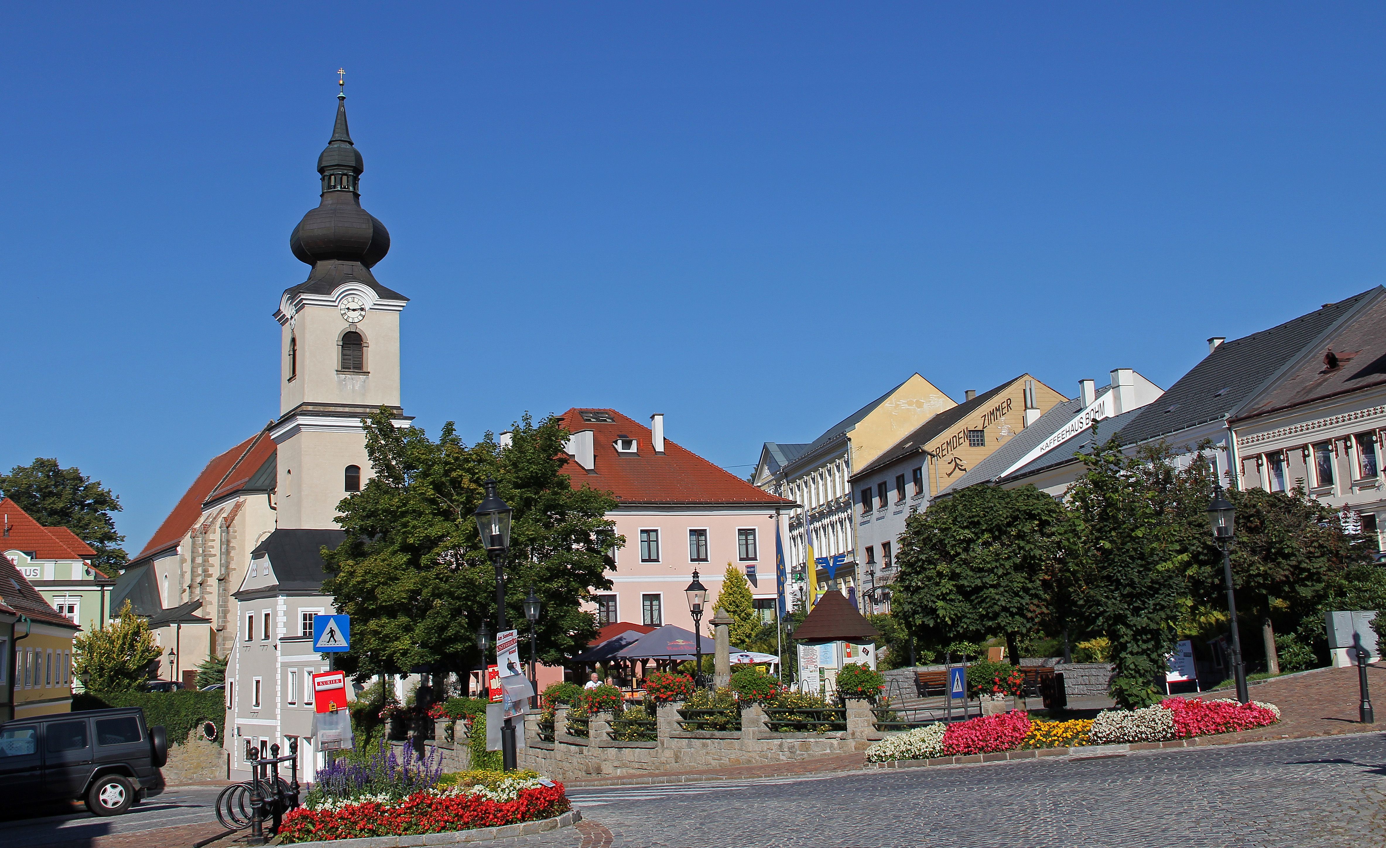 Town square in Heidenreichstein with church and colorful flower beds.