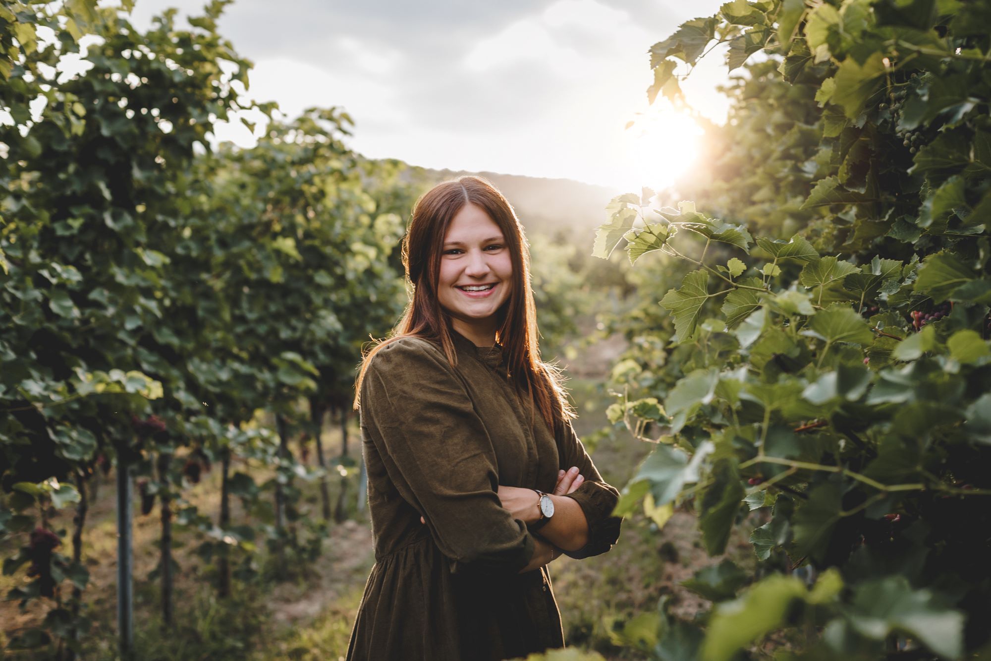 Woman standing between vines.