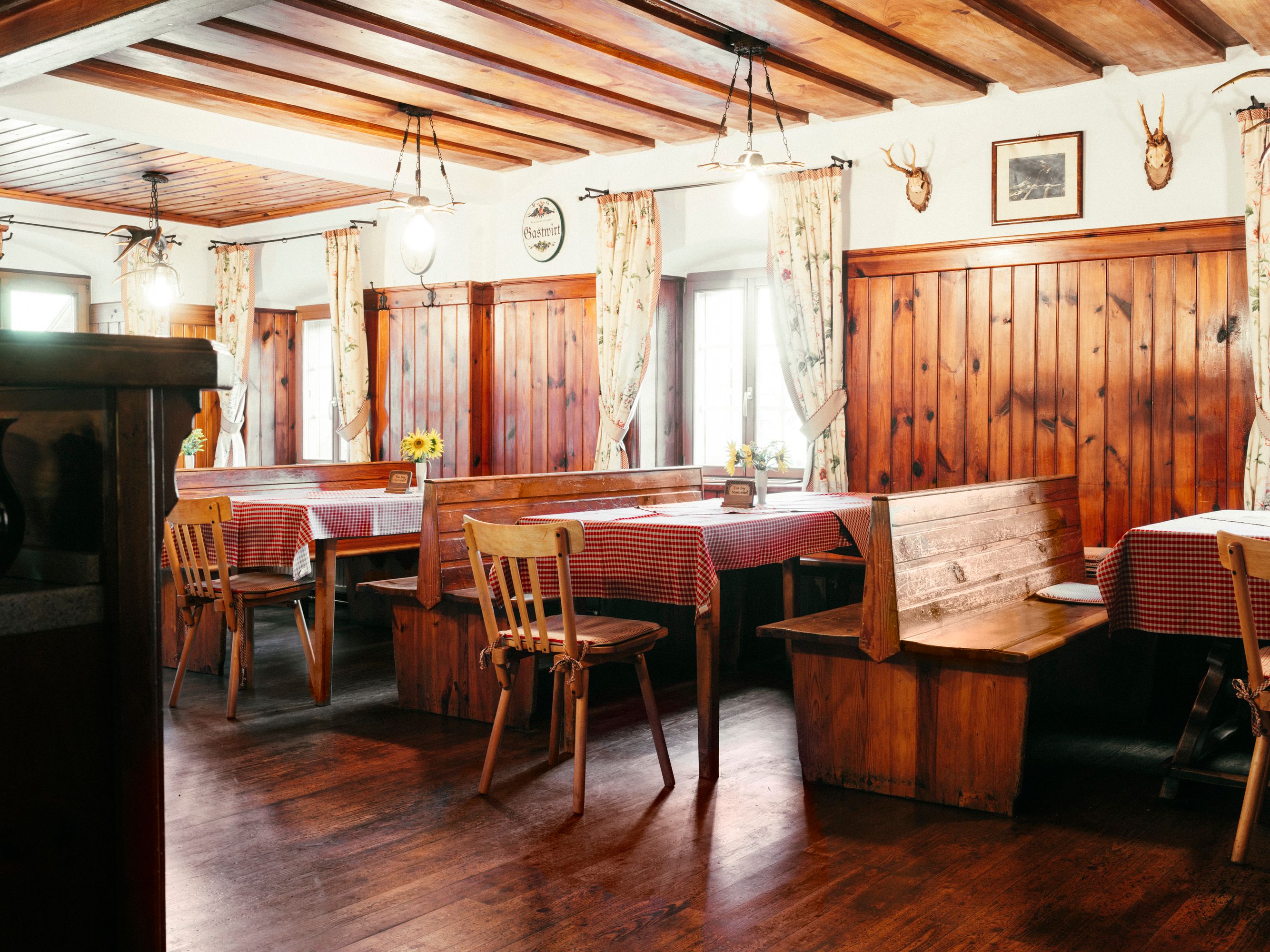 Cozy dining room with wooden furniture and checkered tablecloths.