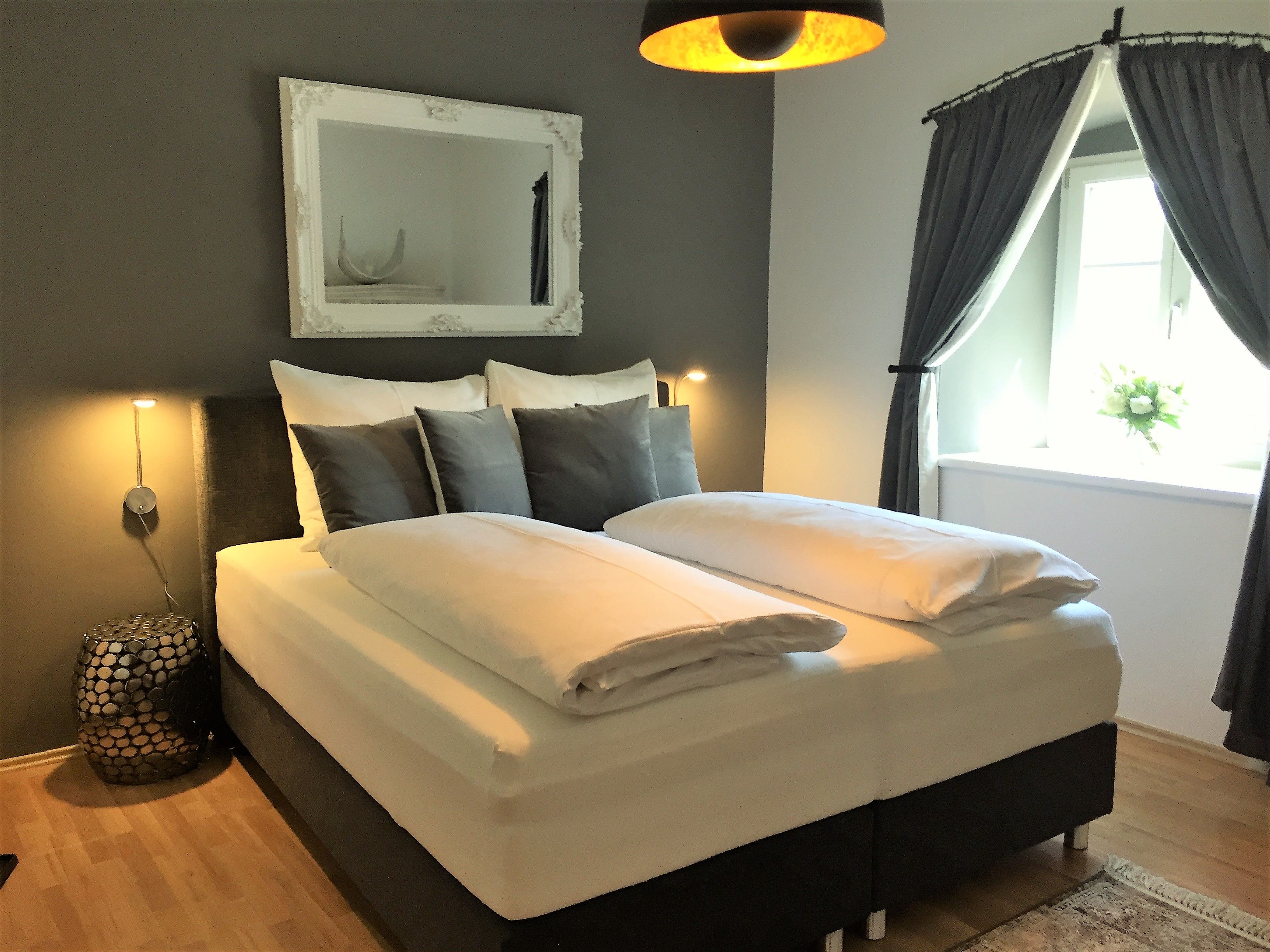 Modern bedroom with double bed, gray walls and decorative mirror.