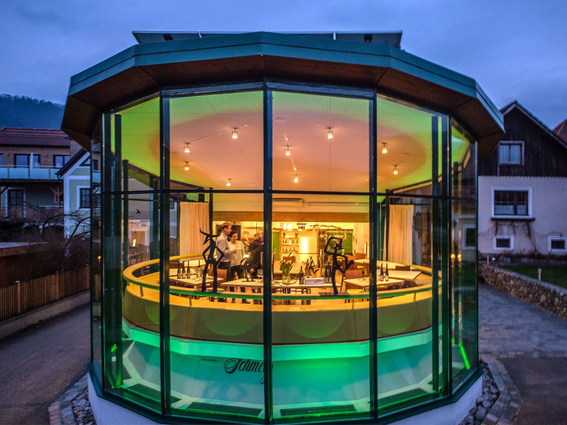 Exterior view of a modern, glazed building at dusk with illuminated interior.