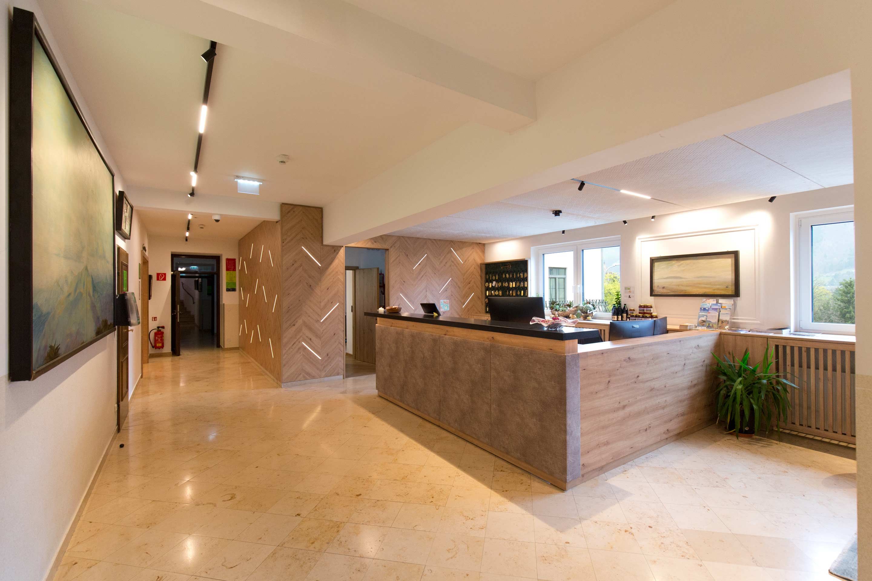 A hotel reception area featuring a modern design, wooden elements, and a large reception desk.