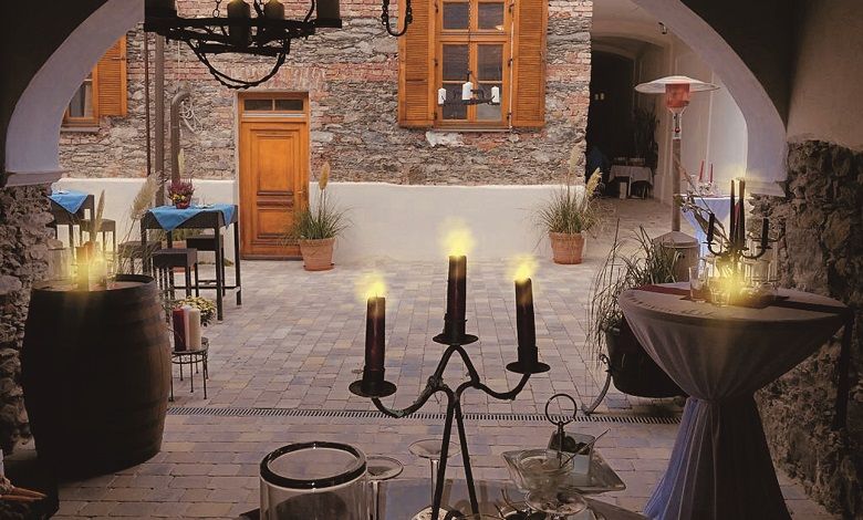 Cozy inner courtyard of a café with candlelight and rustic stone wall.