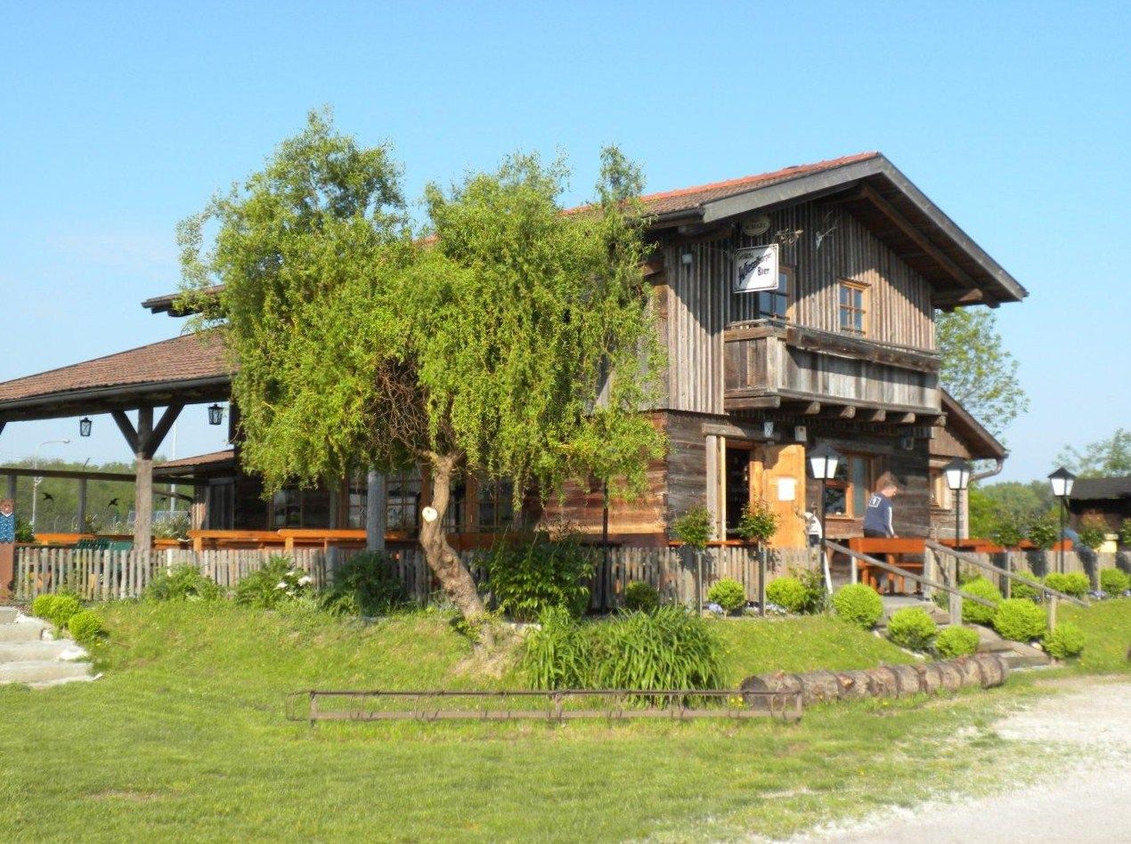 A rustic wooden hut with terrace and garden in the countryside, in sunny weather.
