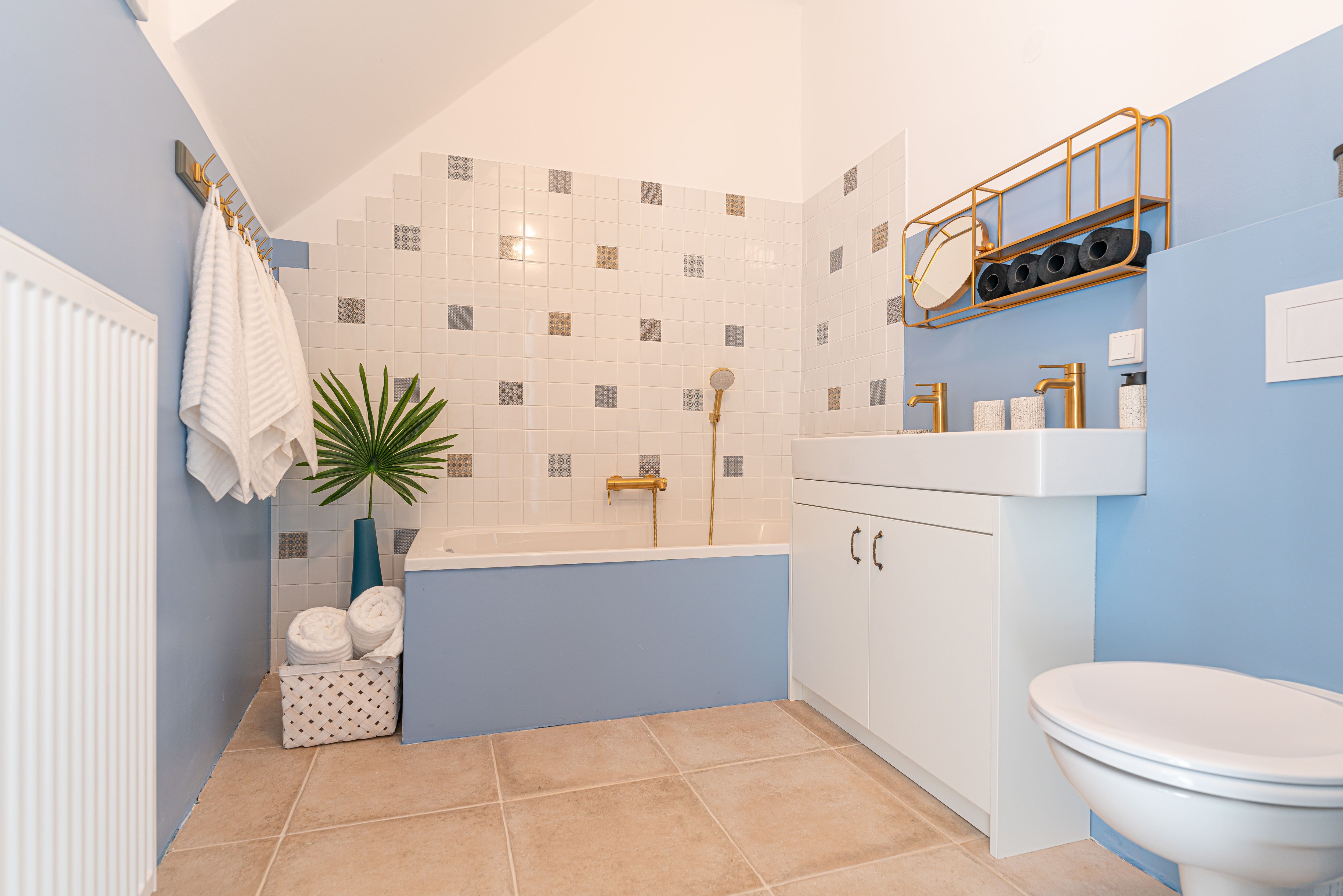 Modern bathroom with blue walls, bathtub, washbasin and golden fittings.