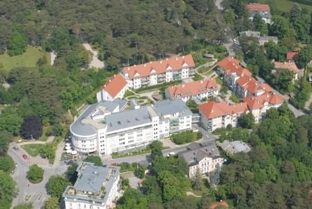 Aerial view of a residential complex with red roofs, surrounded by trees.