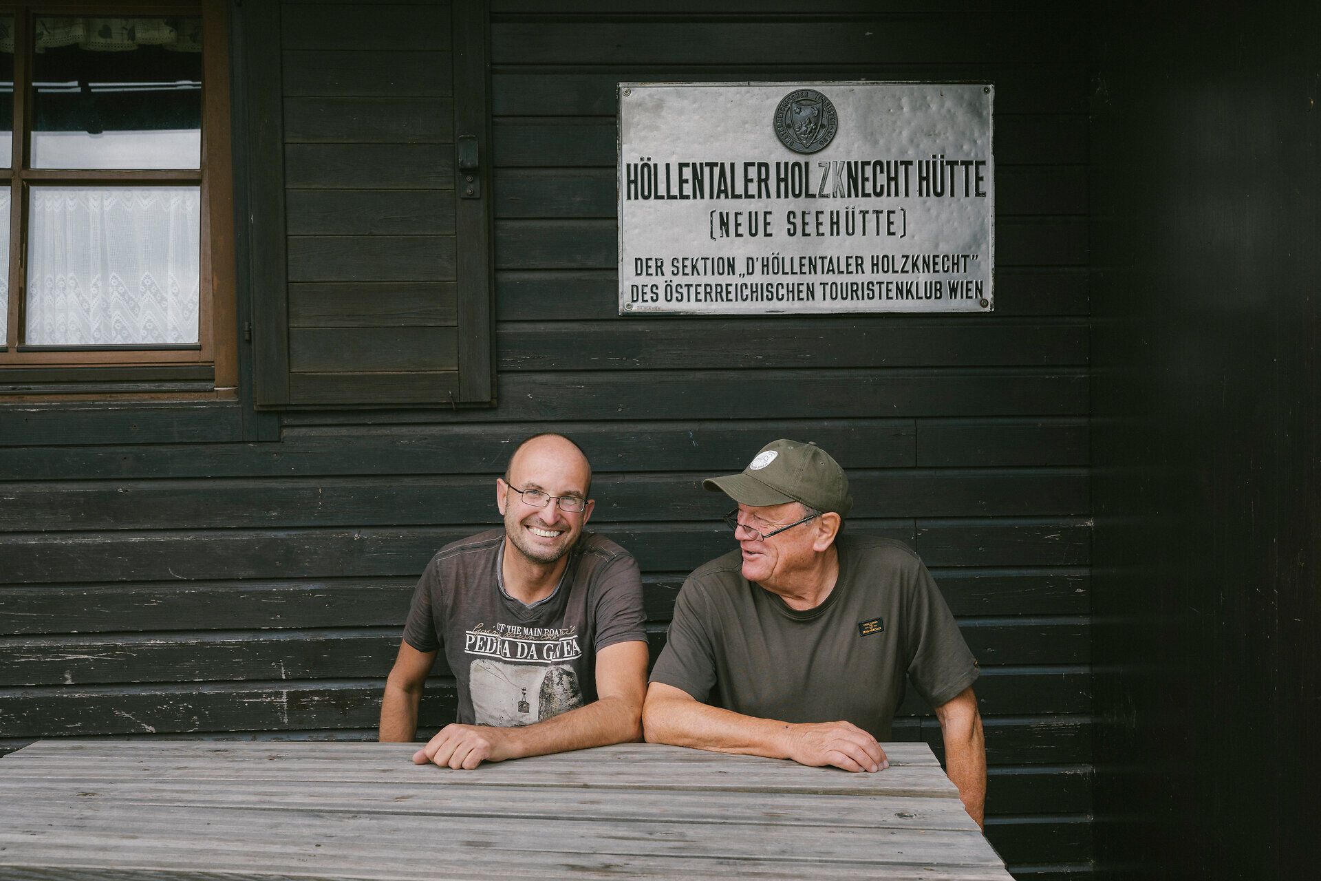 Two lodge owners from the Neue Seehütte on the Rax are sitting together in front of the hut