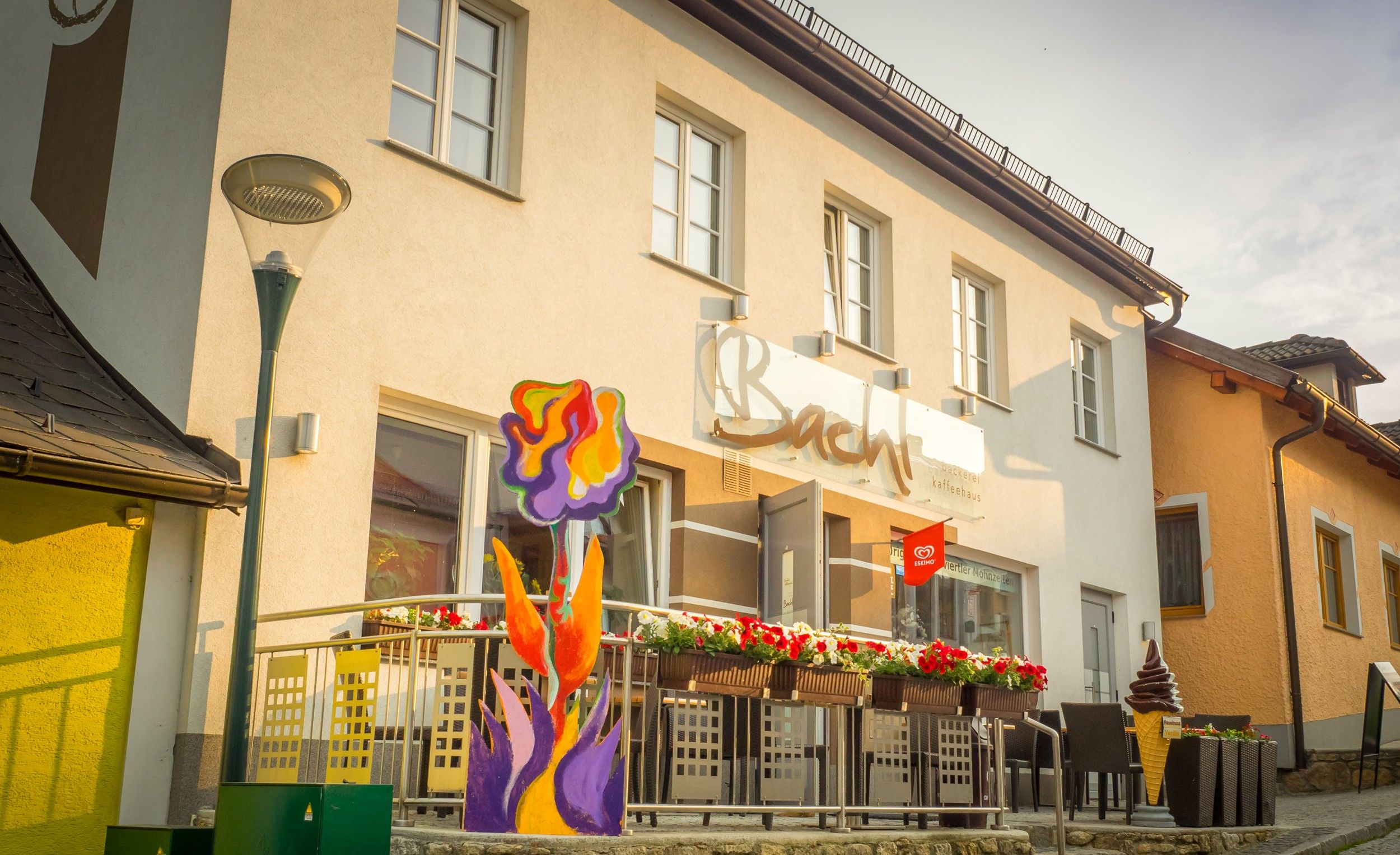 Exterior view of a café with terrace and colorful floral decorations.