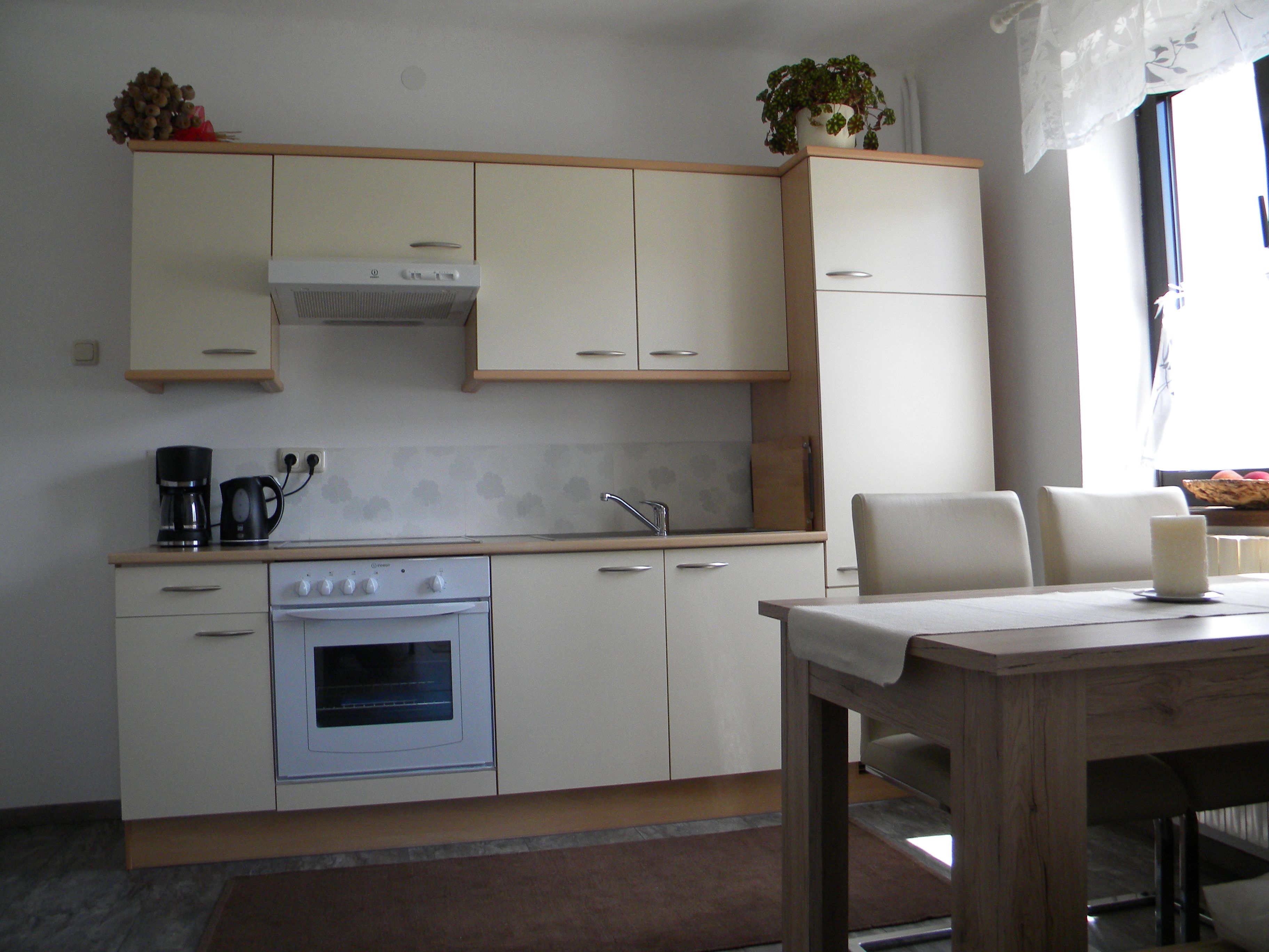 Modern kitchen with cream-colored cabinets, dining table and chairs.