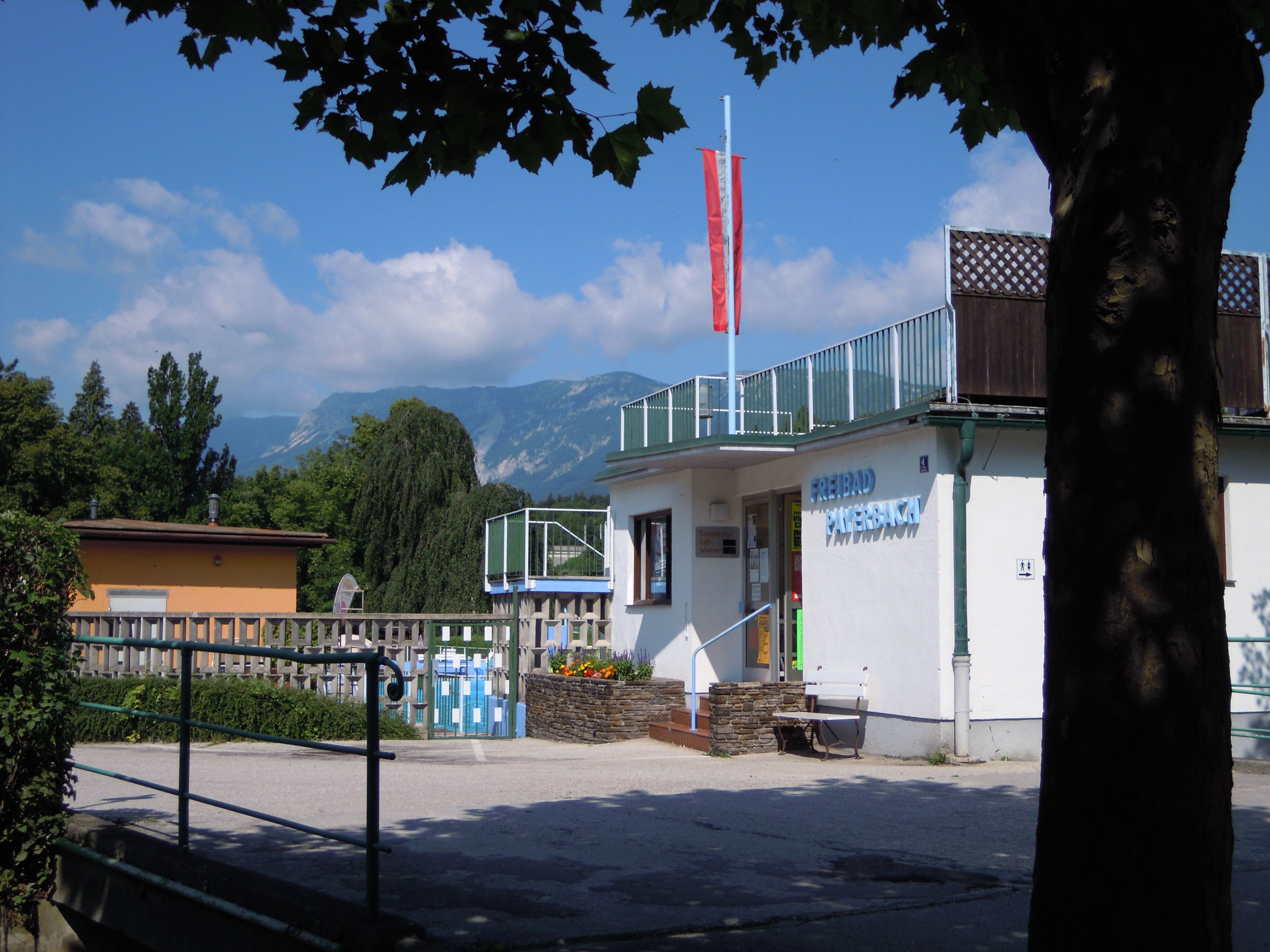Entrance to the Payerbach outdoor pool with mountain landscape in the background.