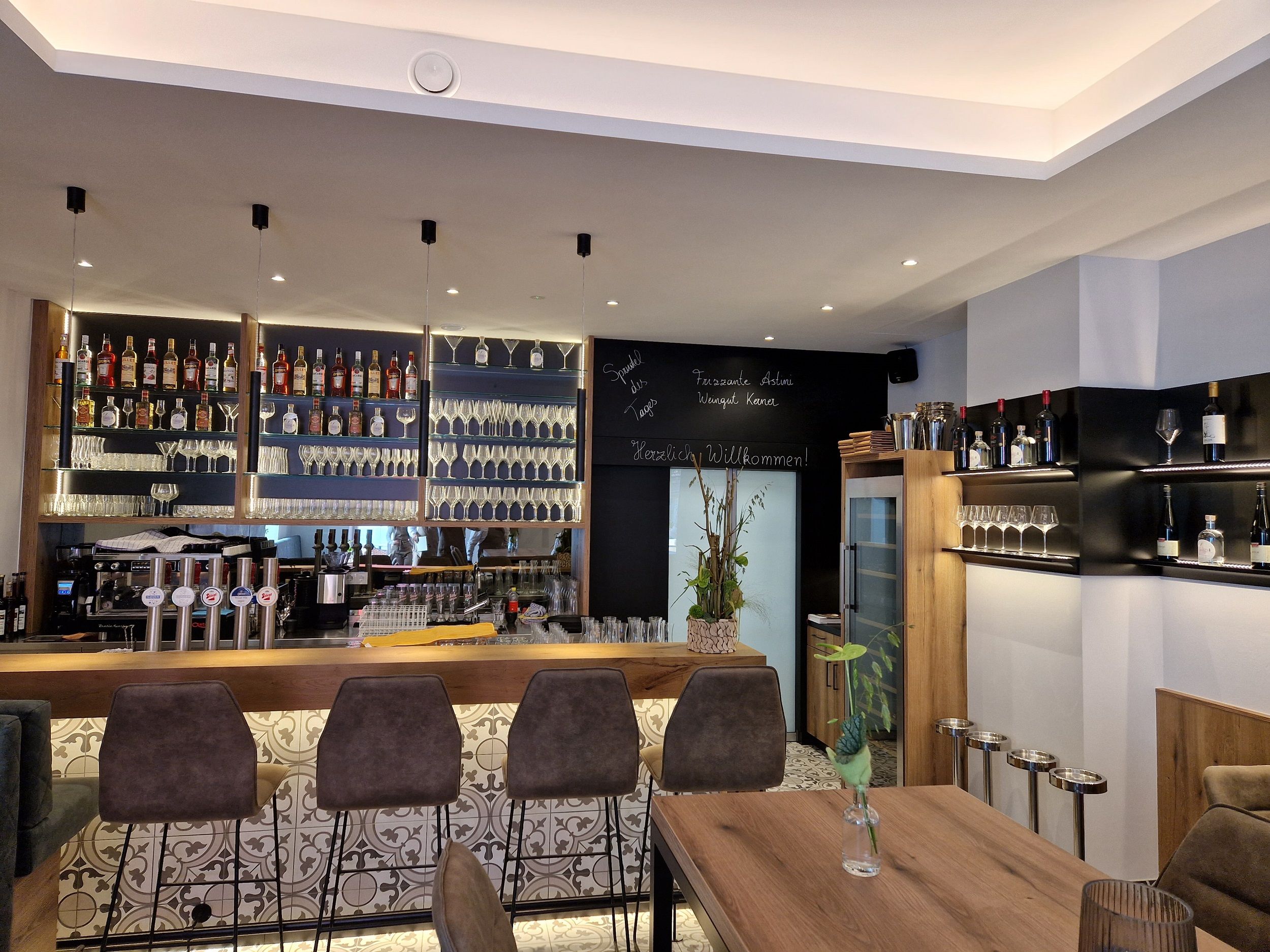 Modern bar with bottle racks, glasses and bar stools.