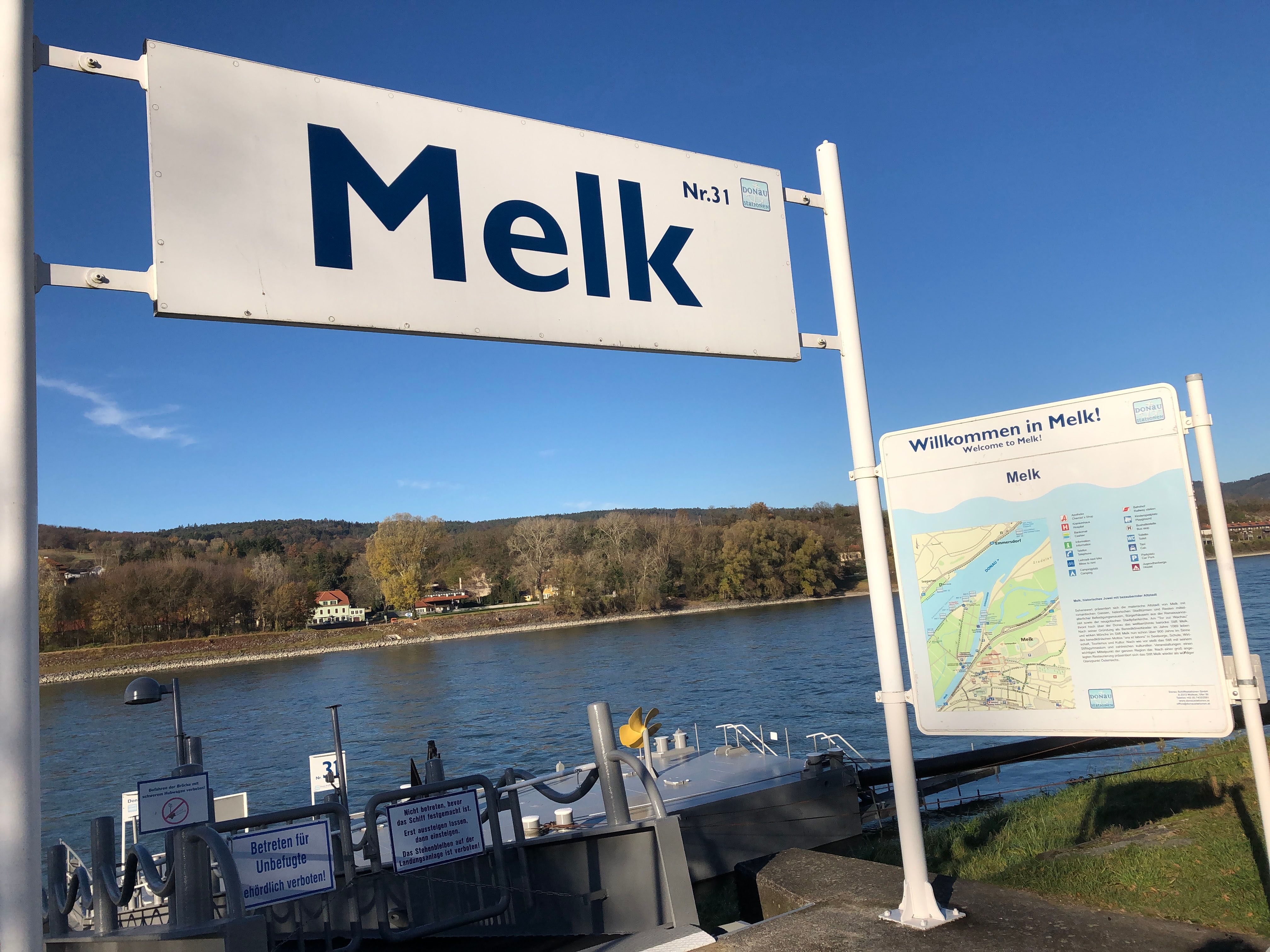 Landing stage in Melk on the Danube with signs and river in the background.