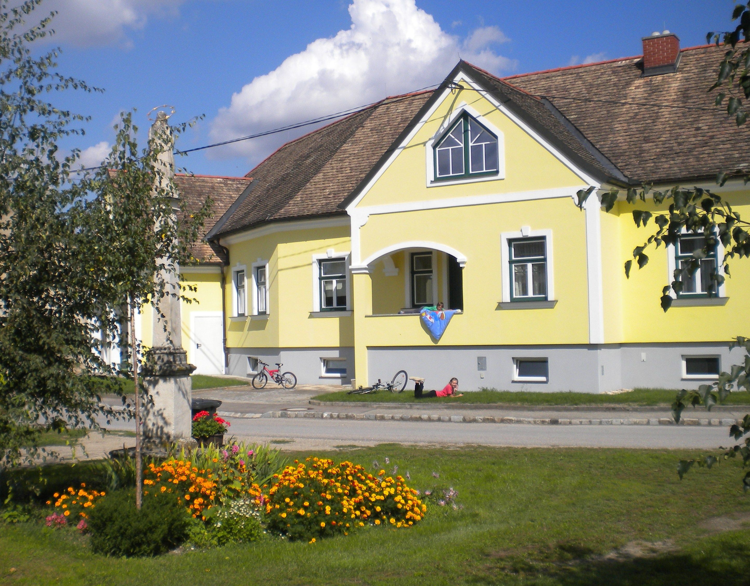 Yellow guest house with flower bed and bicycles in front.
