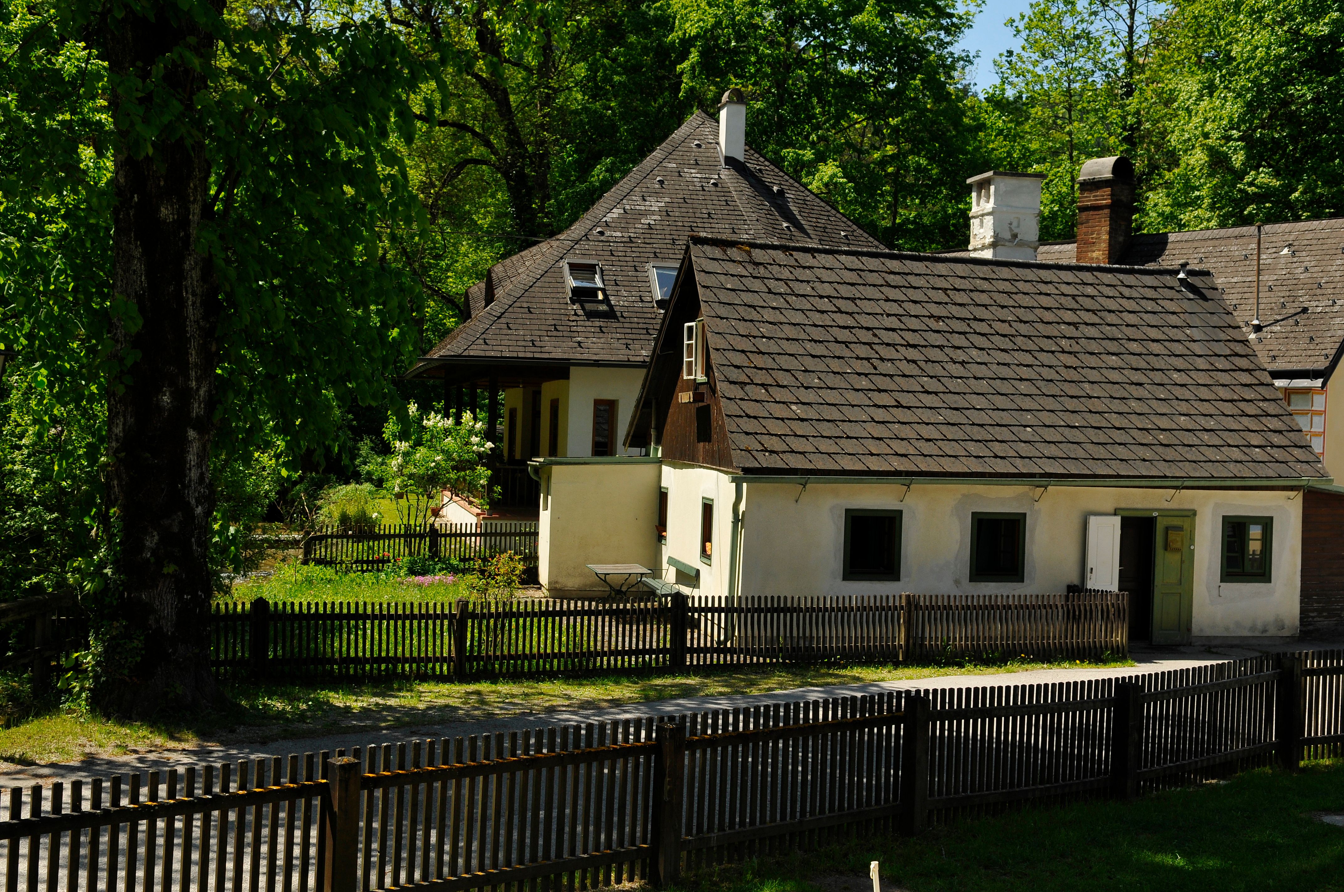 A traditional guest house with wooden fence and garden, surrounded by trees.