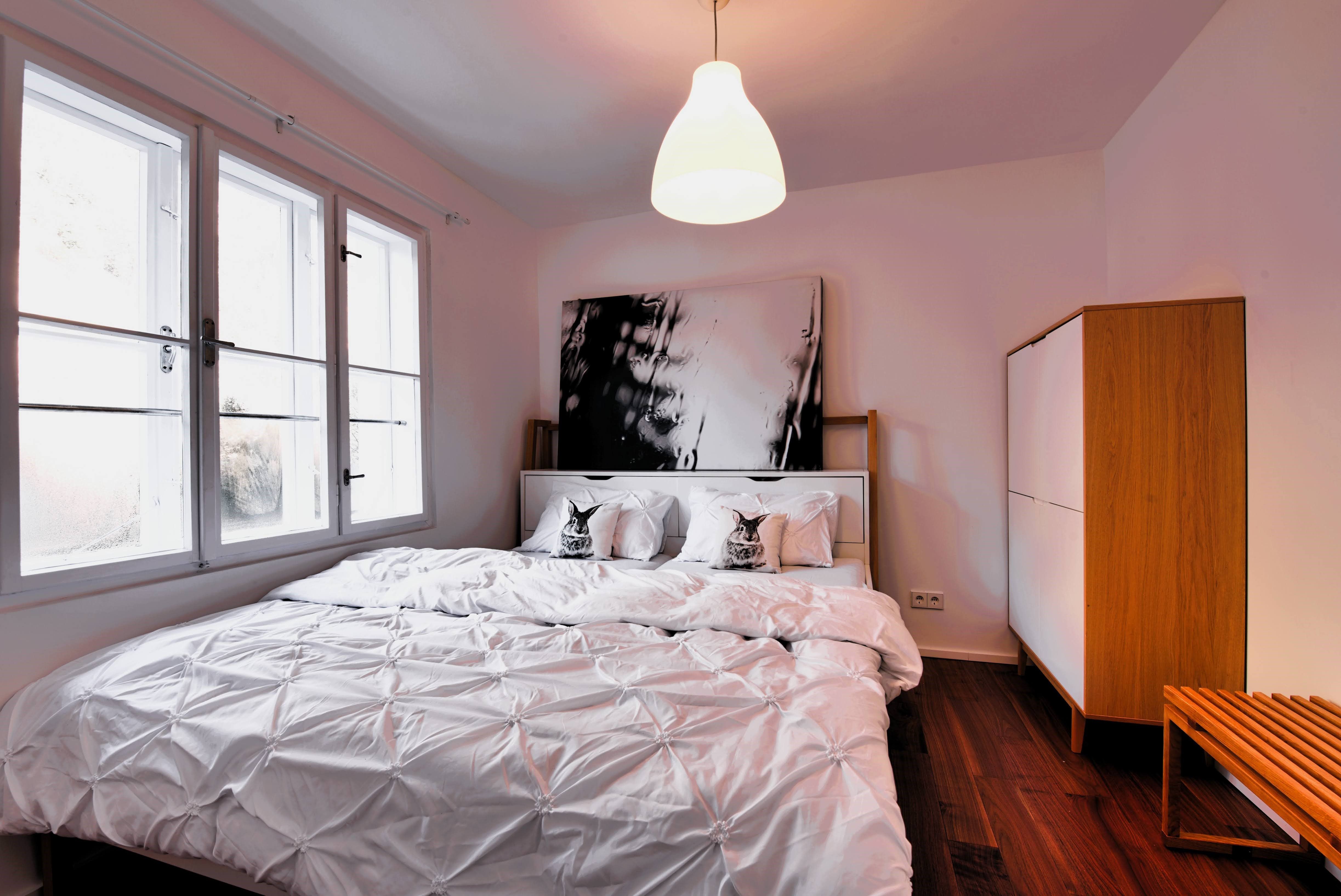 Modern bedroom with large bed, white bed linen and wooden wardrobe.