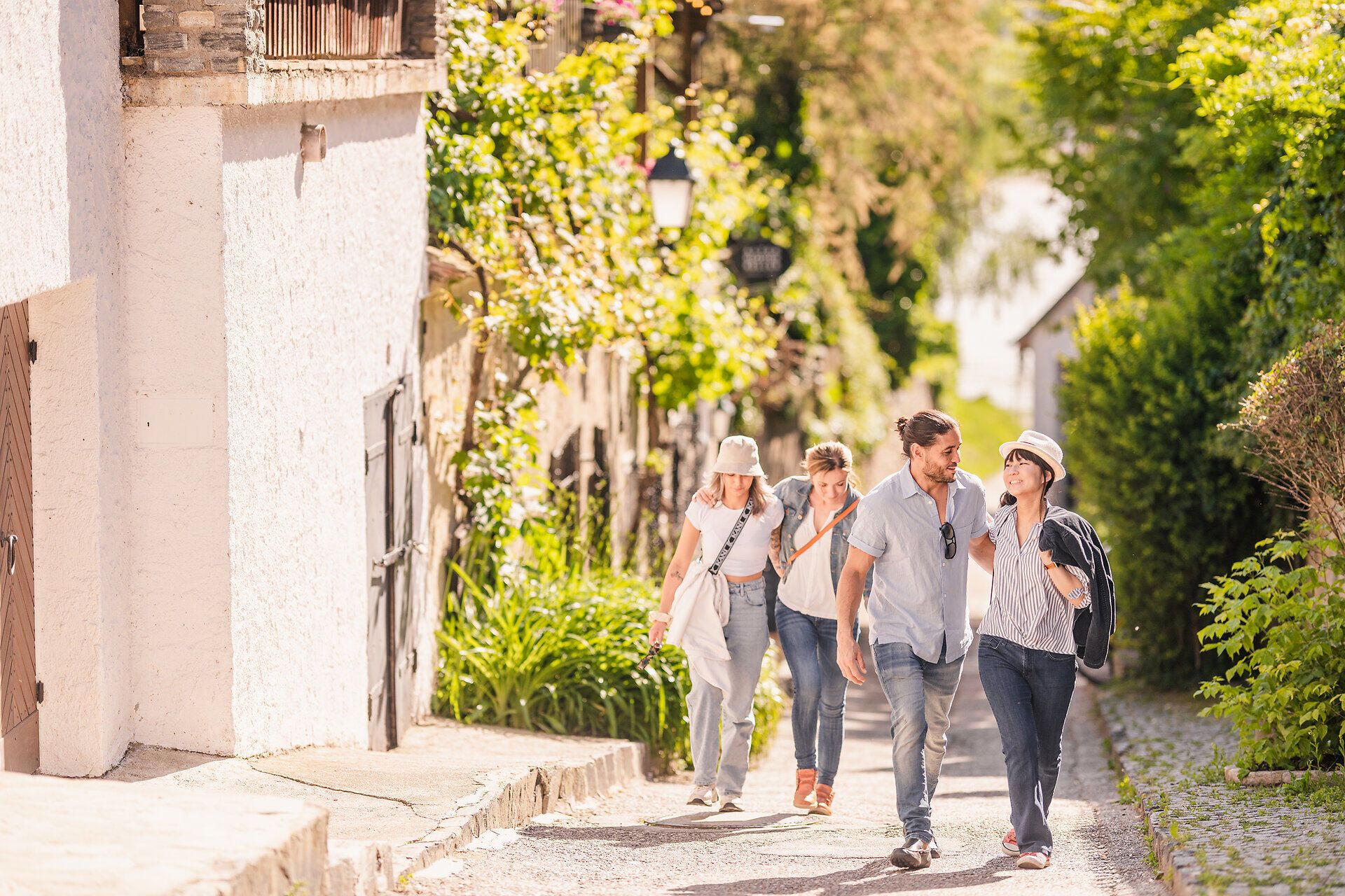 Drei Mädchen und ein junger Bursche schlendern in einer engen Gasse.