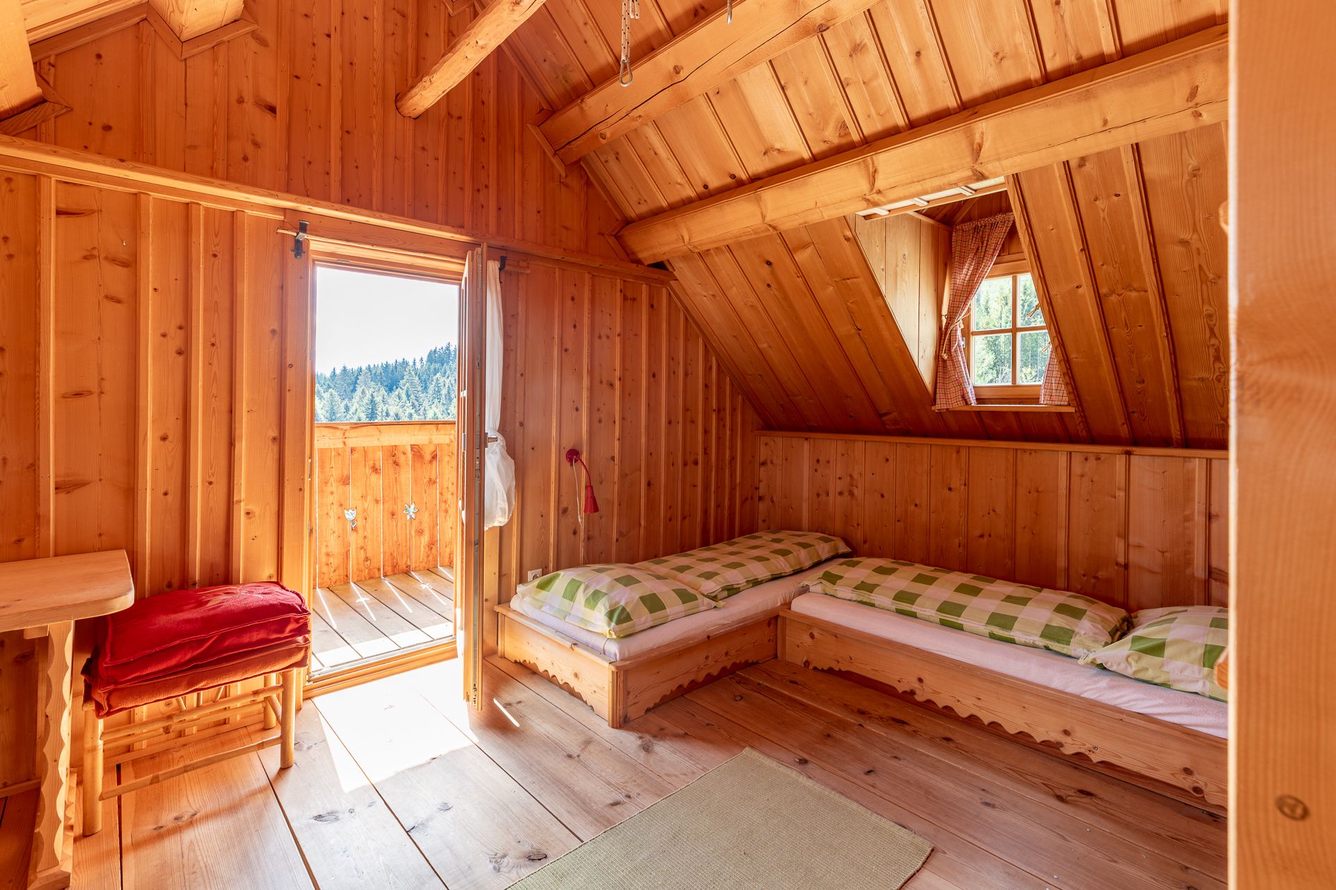 Bedroom with wood paneling, two beds, a window and an open door to the balcony.