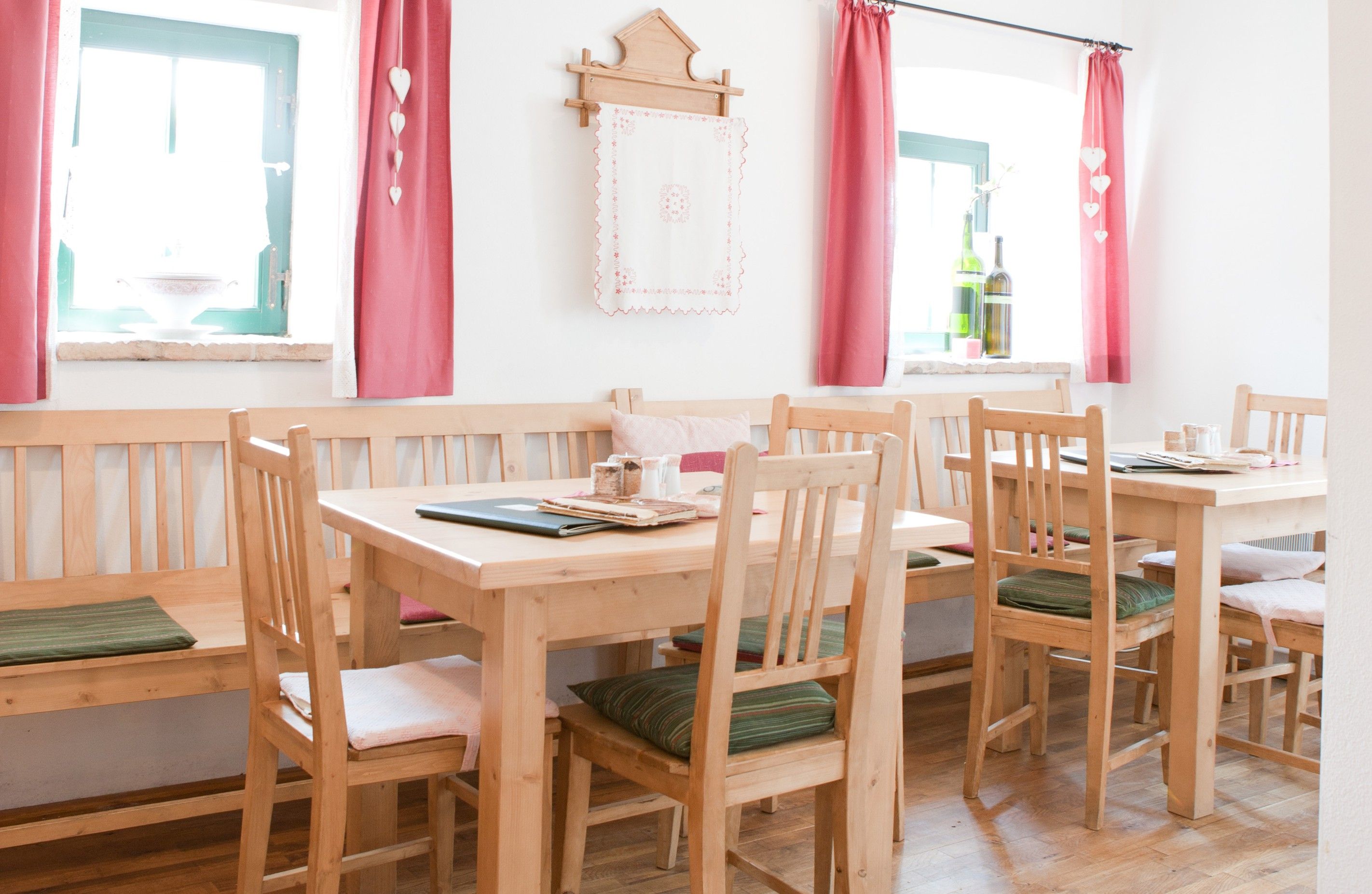 Cozy dining room with wooden furniture, red curtains and decoration.