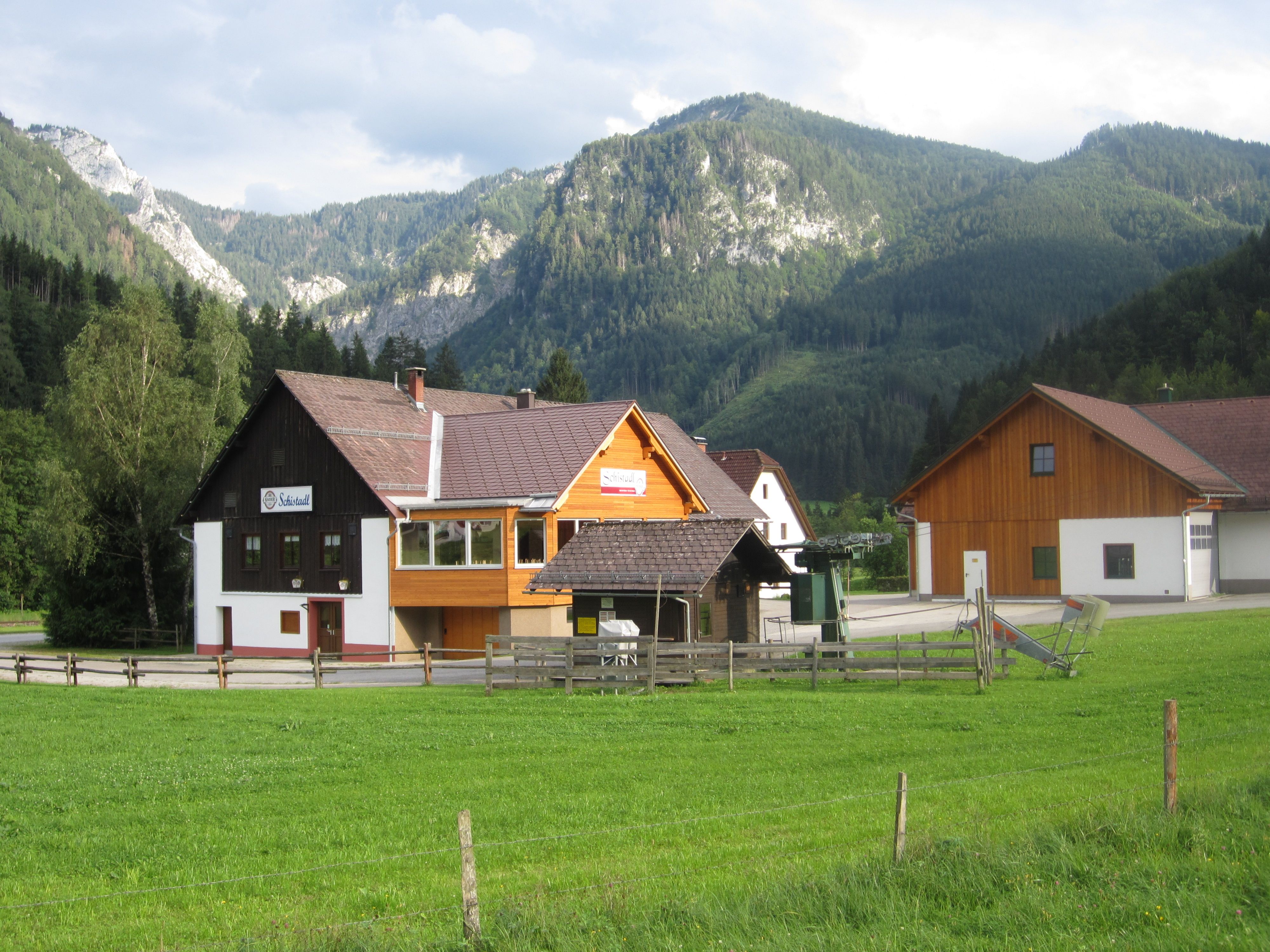 A building with the inscription 'Schistadl' in front of a mountain landscape.