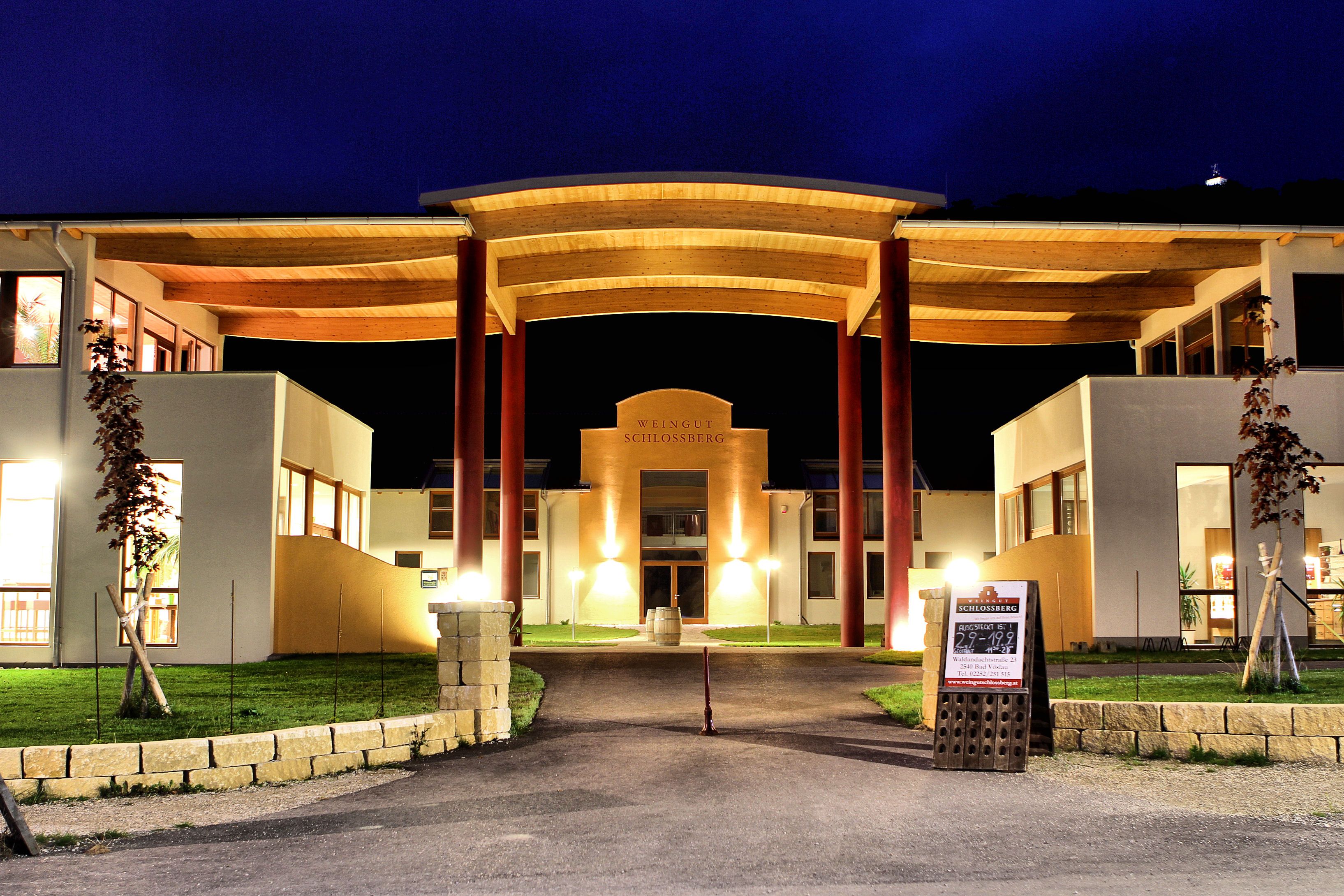 Illuminated building of the Schlossberg winery at night.