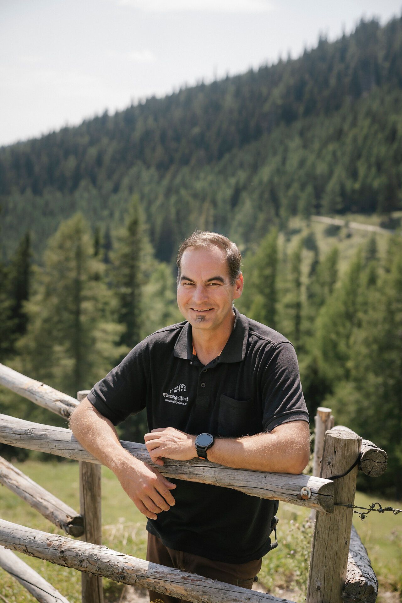 The owner of the Waxriegelhaus lodge on the Rax stands against a backdrop of alpine mountain scenery