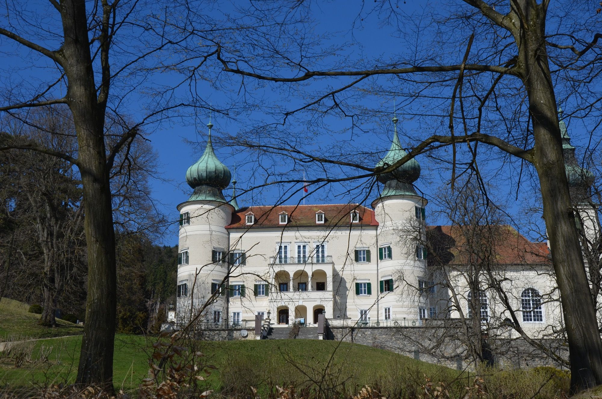 Artstetten Castle with two striking towers and blue sky in the background.