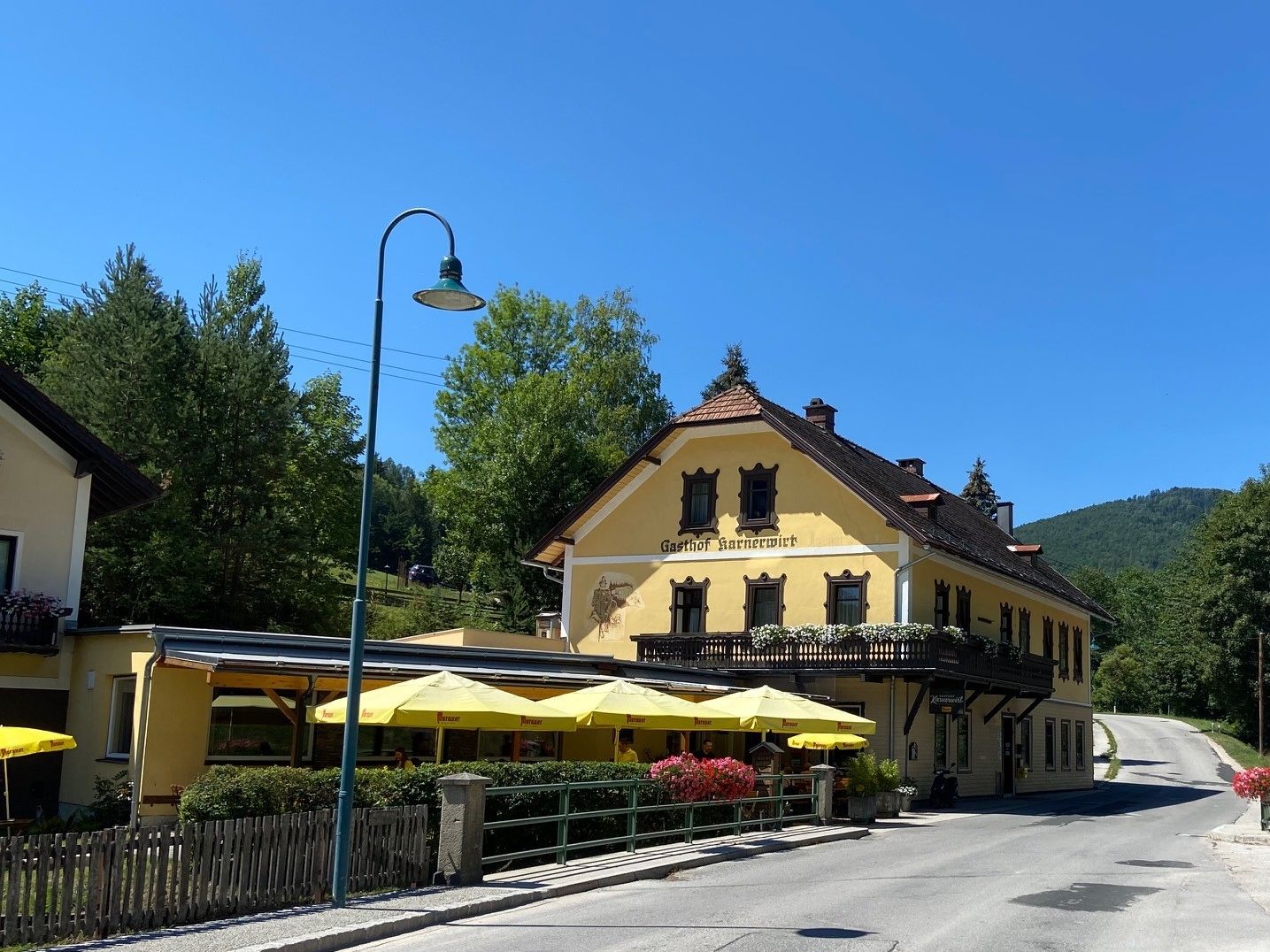 A yellow inn with a balcony and parasols against a blue sky.