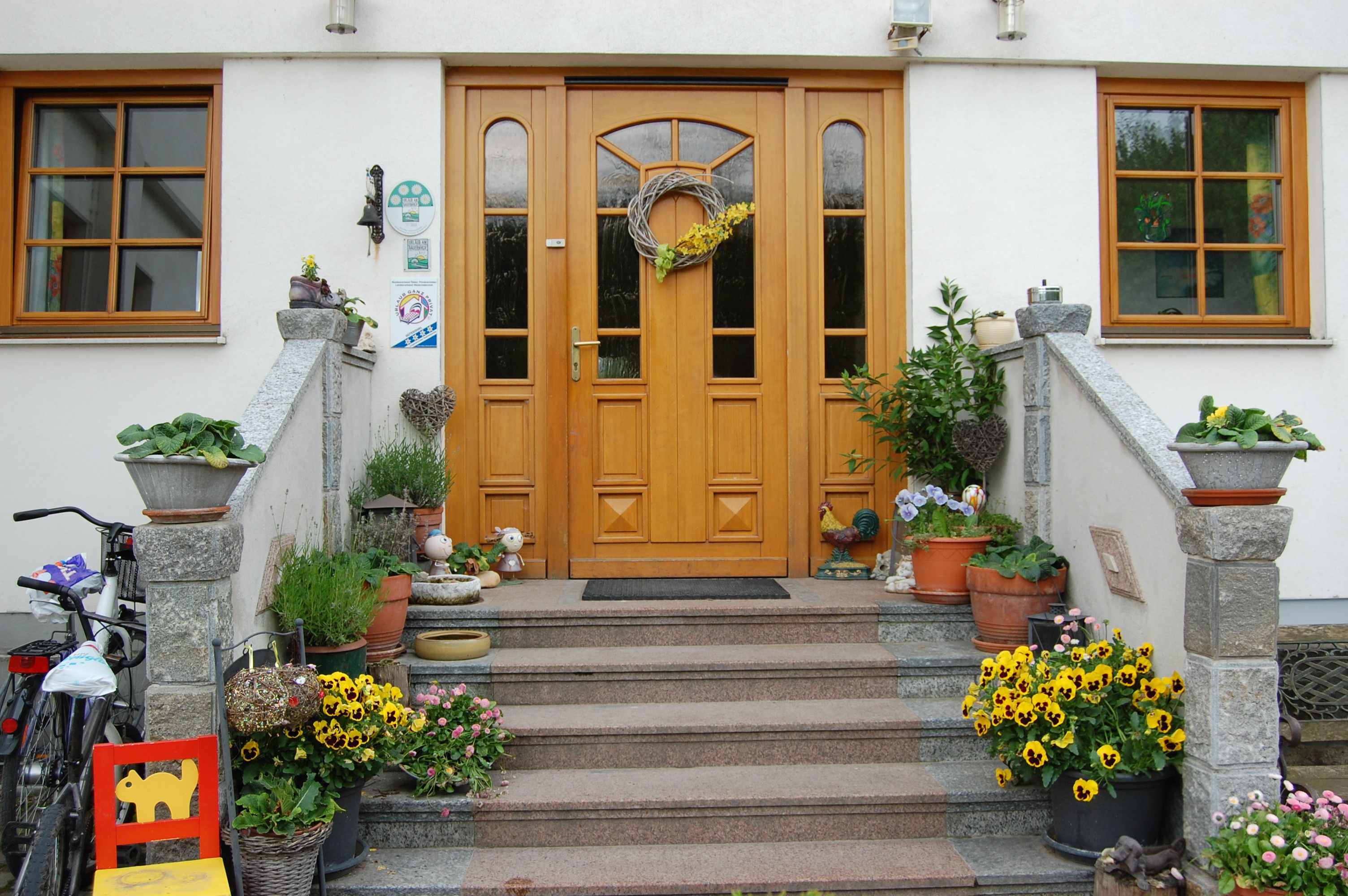 Front of a house with wooden door, staircase and floral decoration.