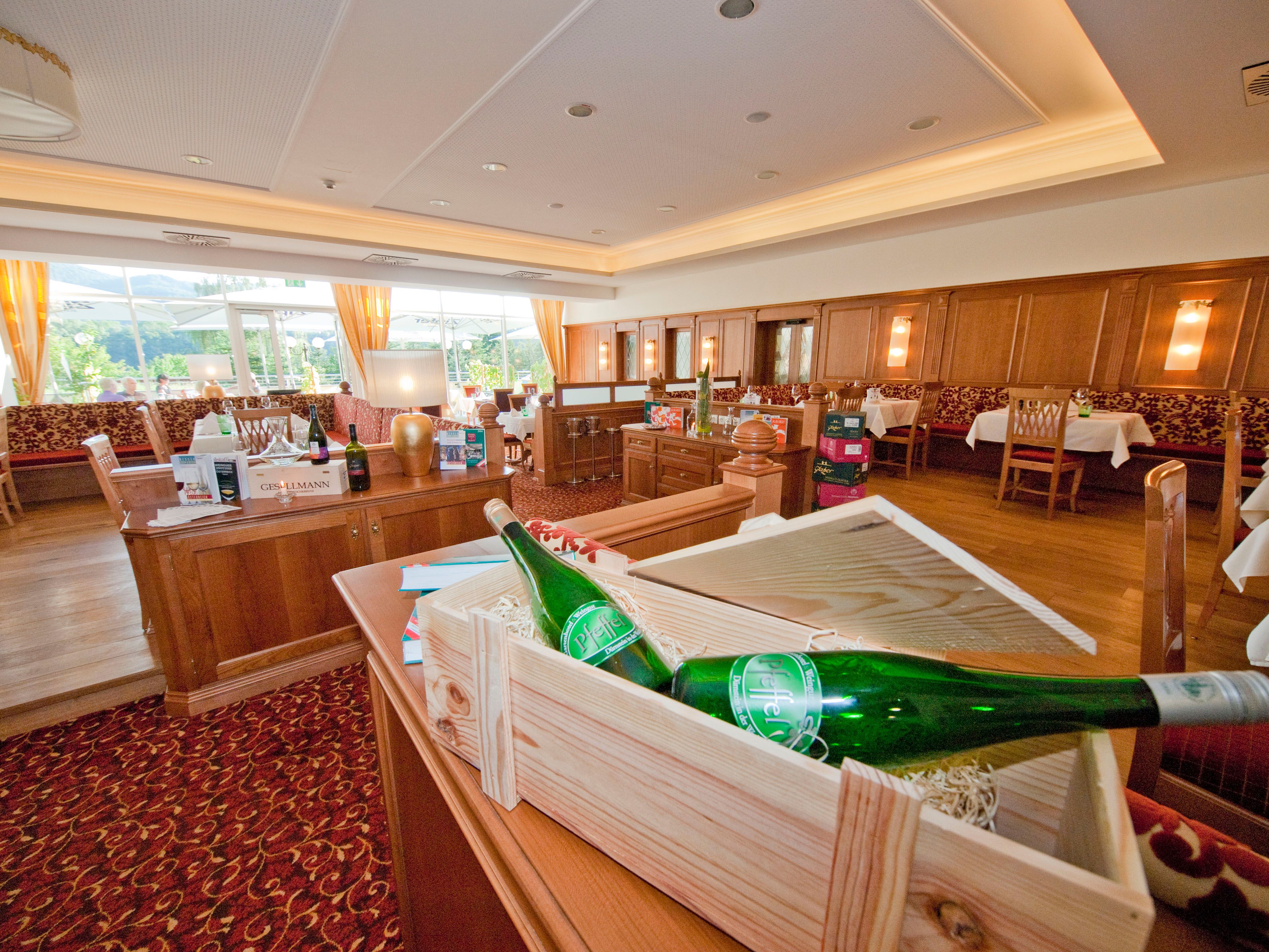 Interior view of an elegant restaurant with wooden furniture and bottles of wine.