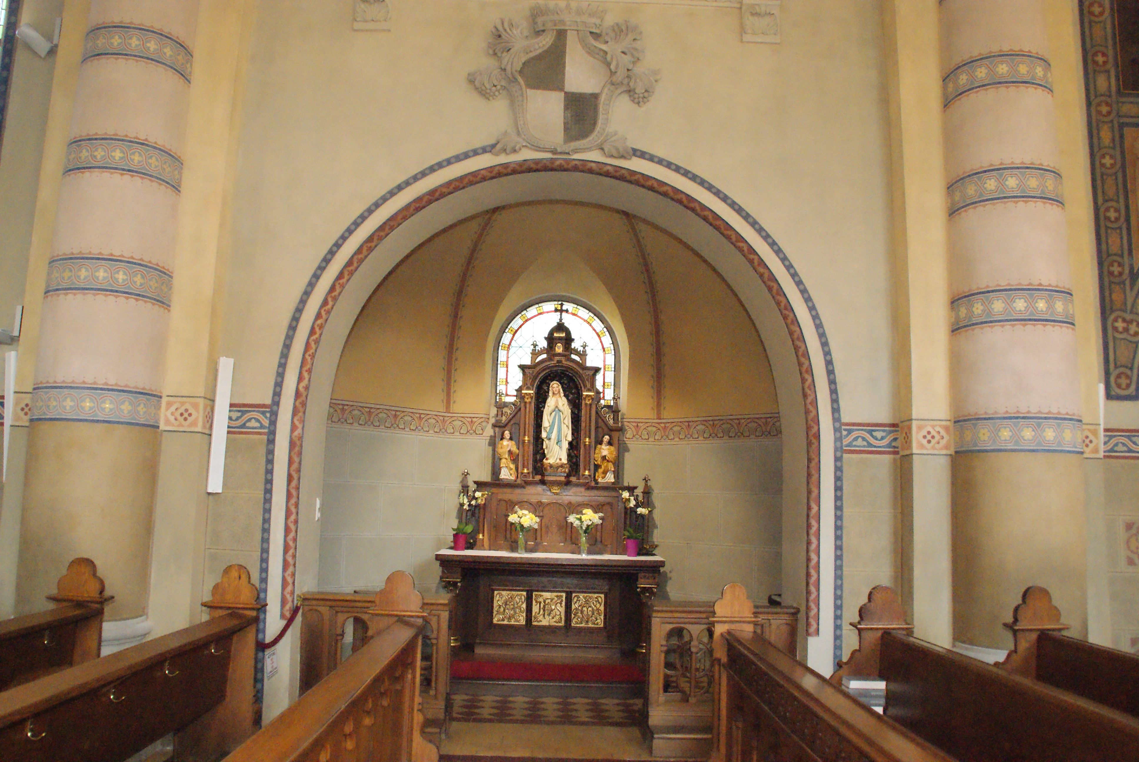 Interior view of a church with an altar and a statue of the Virgin Mary.