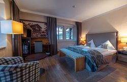 Hotel room with double bed, armchair, table and window with a view.