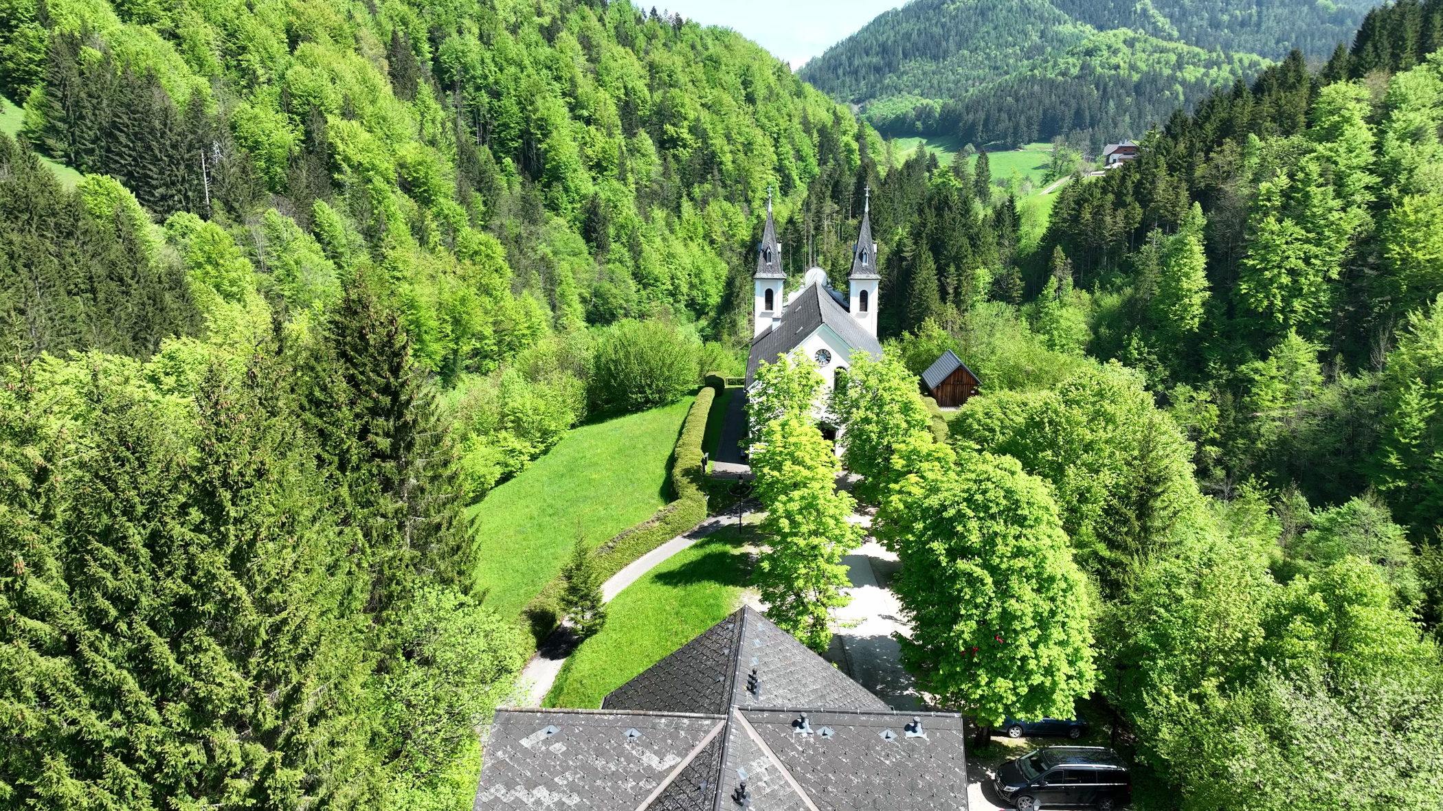Aerial view of the Maria Seesal pilgrimage church, surrounded by green forests and hills.