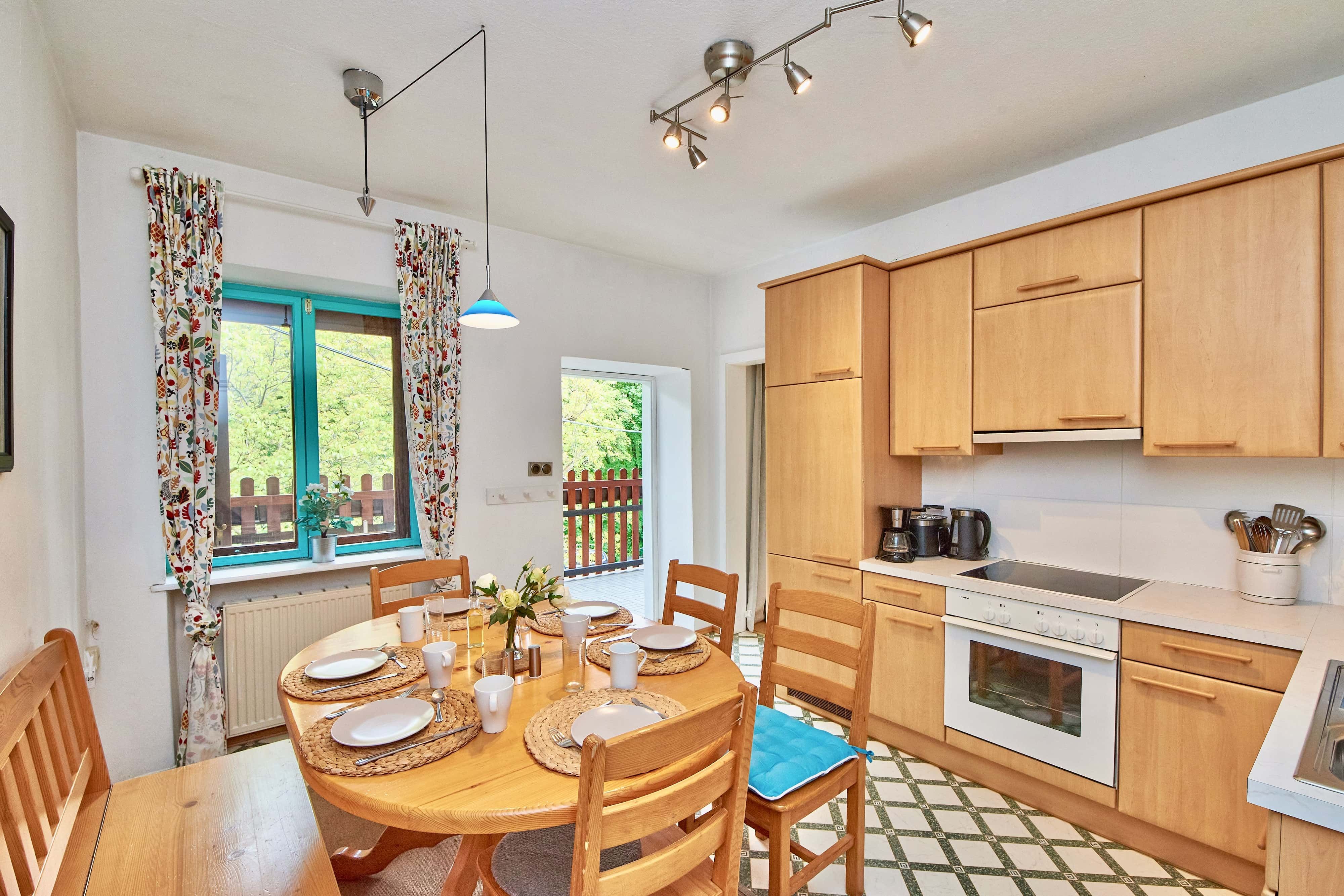 Cozy kitchen with wooden furniture, dining table and windows with colorful curtains.